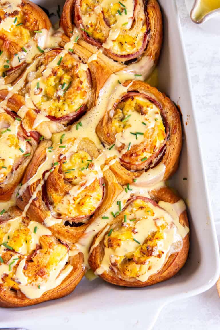 Close-up of flaky Eggs Benedict Breakfast Roll drizzled with hollandaise sauce.