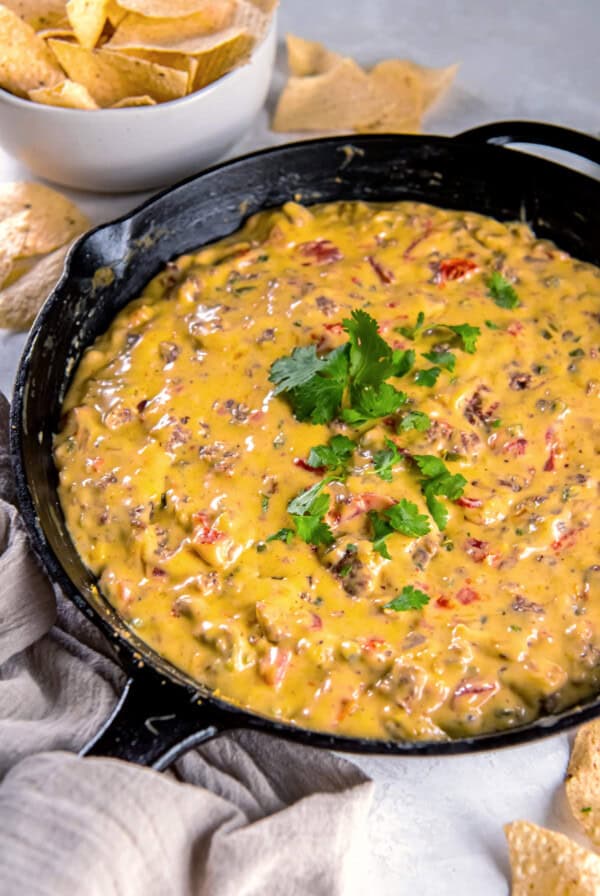 Close-up of hot cheesy queso dip in a skillet with cilantro garnish.