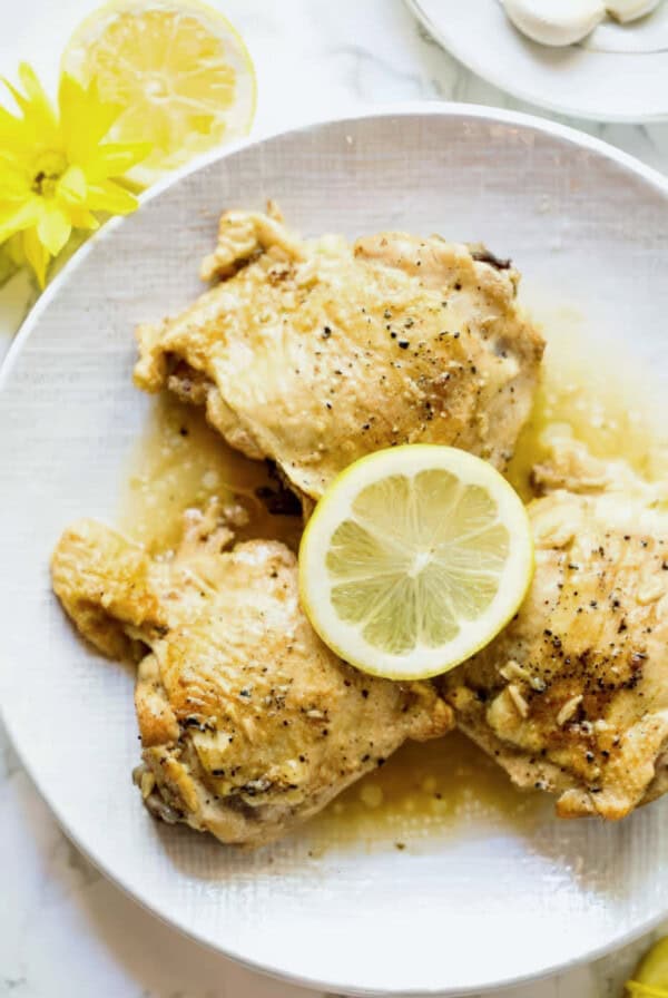 Garlic Butter Chicken Thighs in Instant Pot served on a plate with lemon slice and flowers