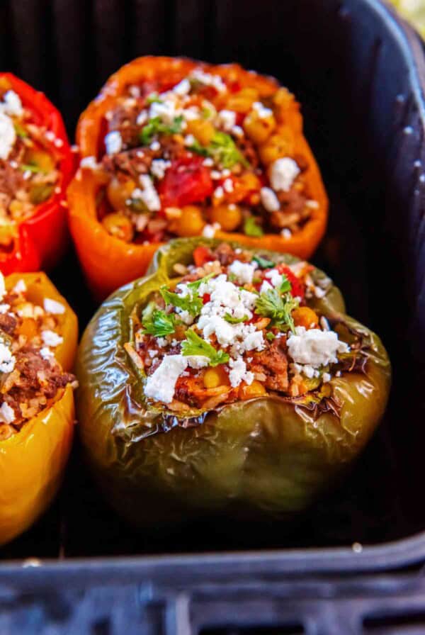 Close-up of cooked Greek stuffed peppers in an air fryer, filled with a savory mixture of beef, rice, chickpeas, and herbs, finished with crumbled feta.