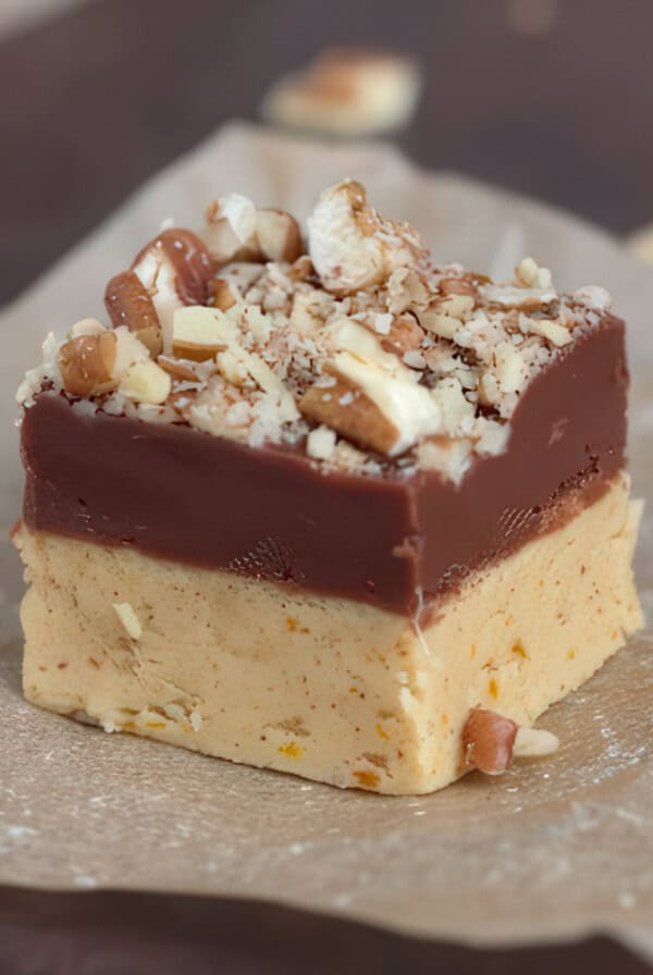 Close-up of a piece of chocolate pumpkin fudge with chopped pecans on top.