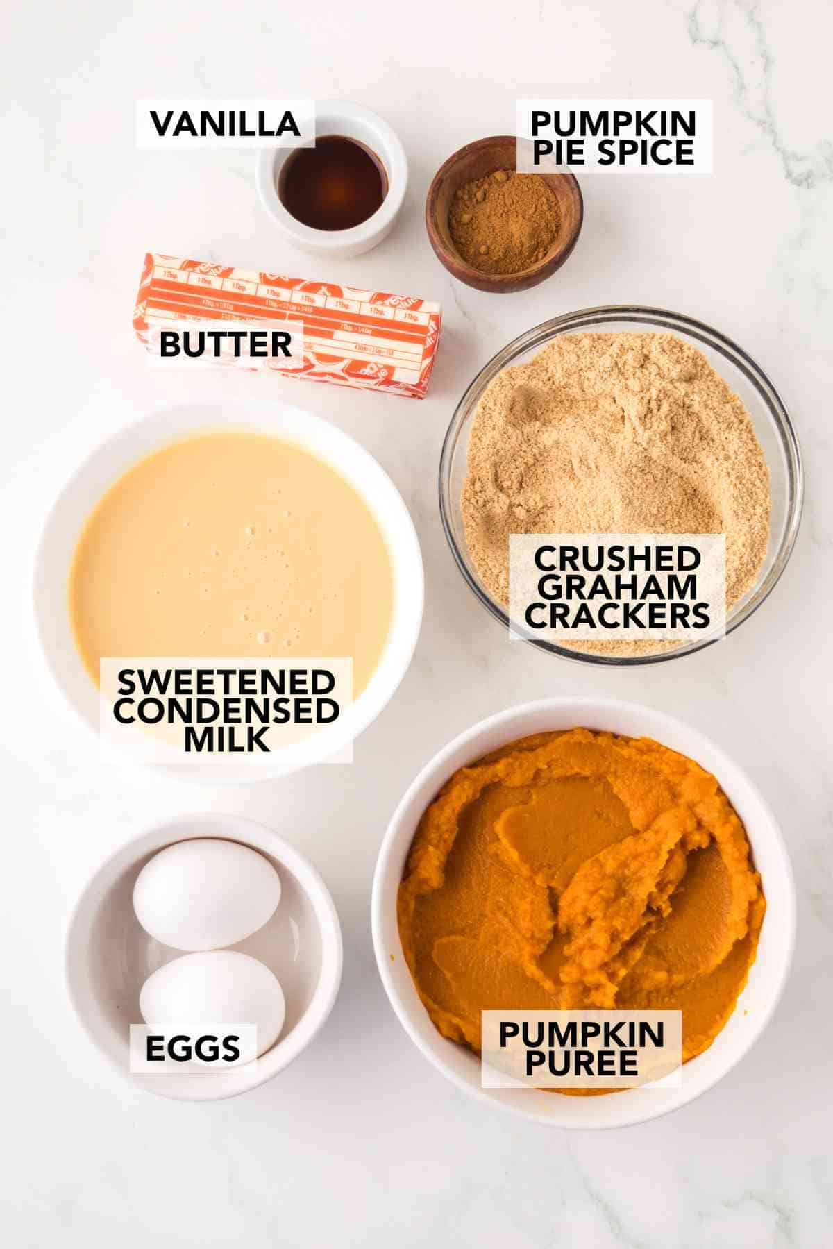 Ingredients for mini pumpkin pies including pumpkin purée, graham crackers, eggs, and spices.