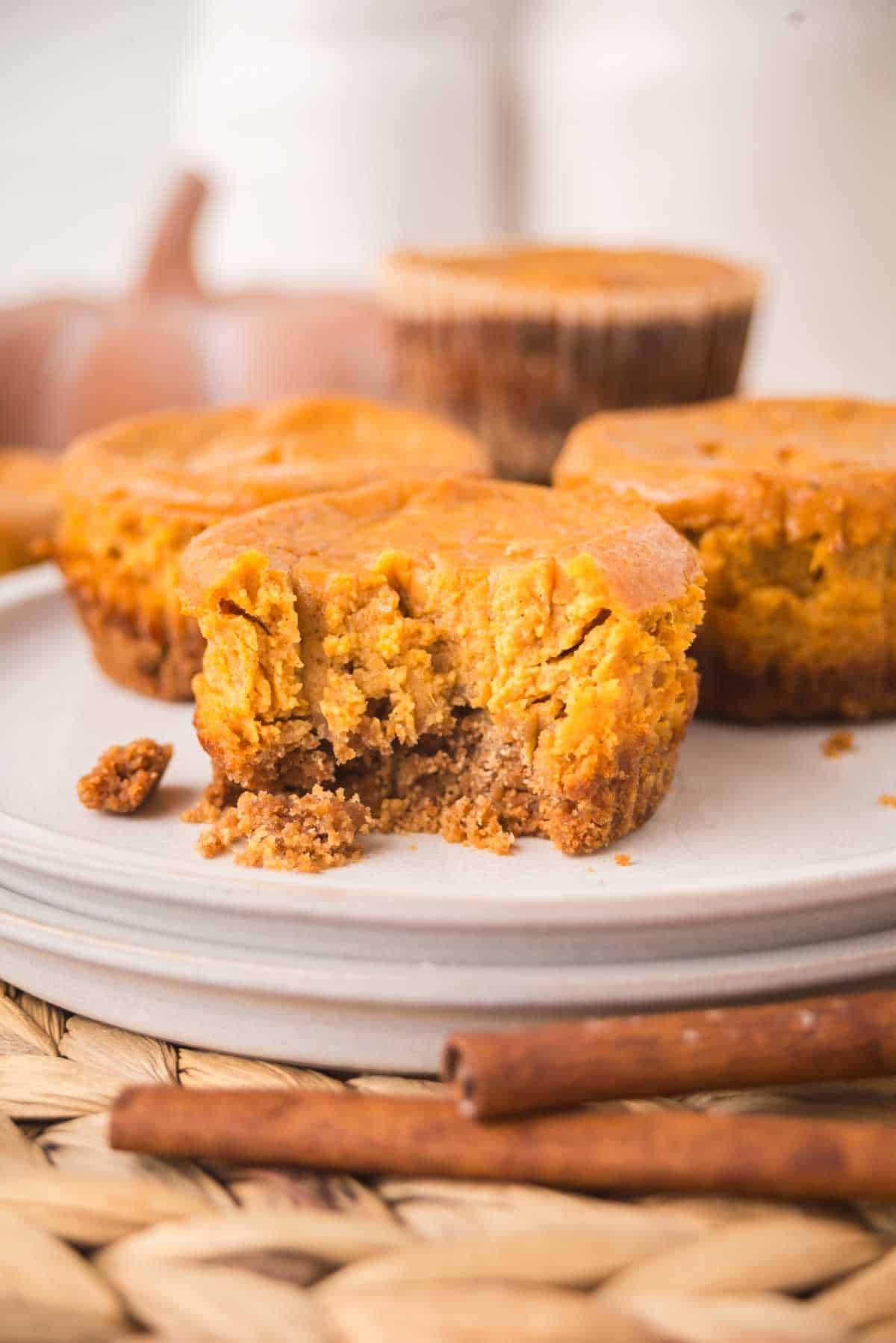 A mini pumpkin pie with a bite taken out, showing creamy pumpkin filling and crunchy crust.