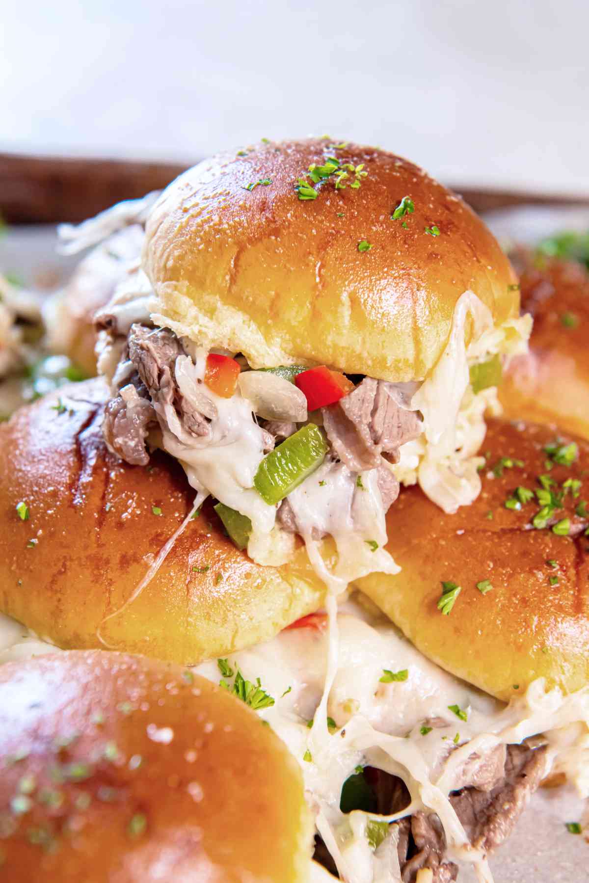 Close-up of a cheesesteak slider showing melted cheese, peppers, and steak inside the bun.