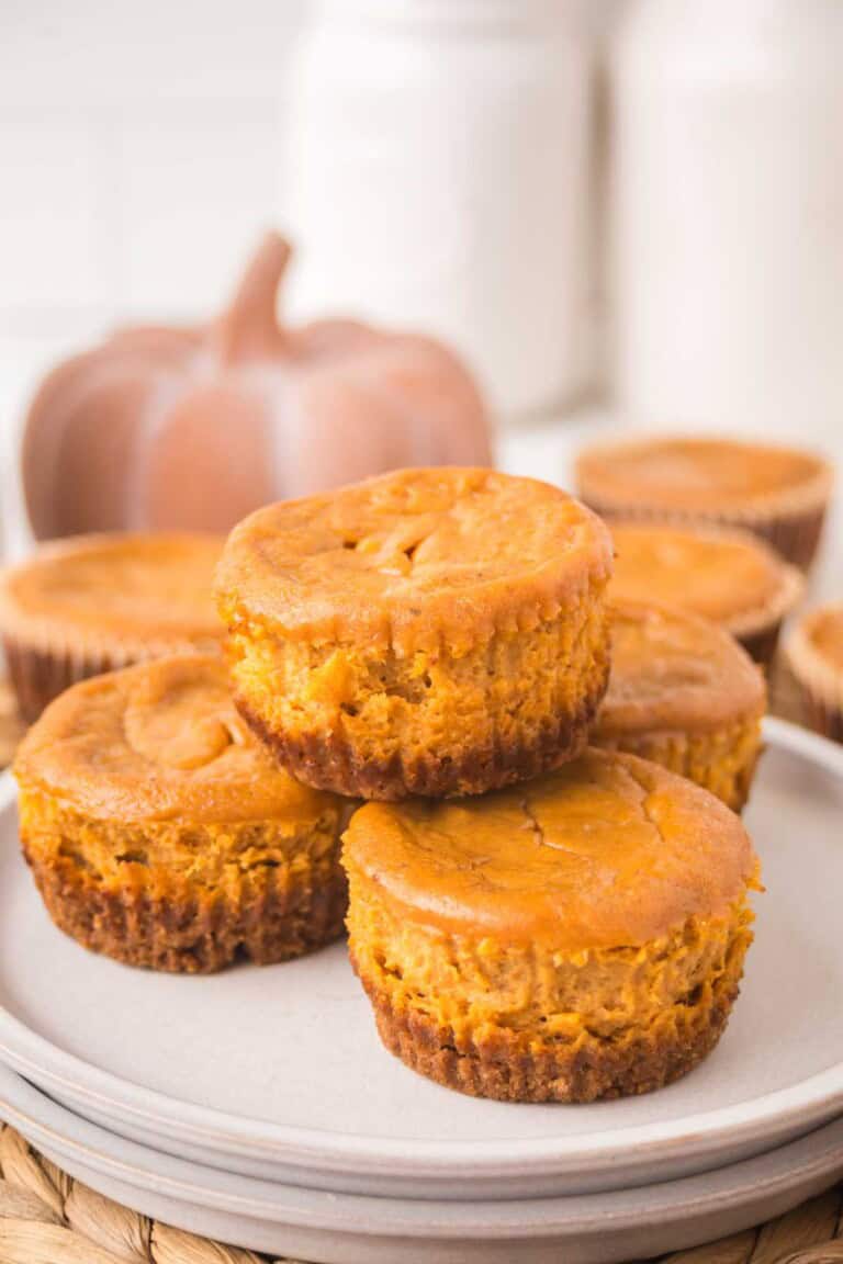 A stack of mini pumpkin pies showing the graham cracker crust and soft pumpkin pie filling.