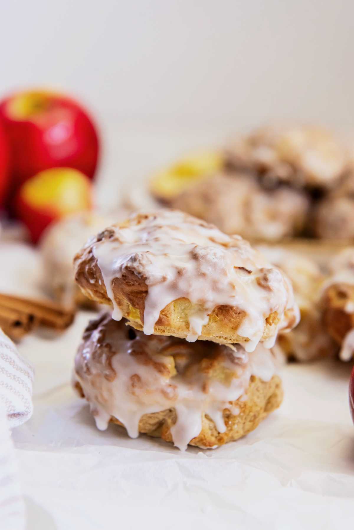 Two applesauce fritters stacked with vanilla glaze dripping down the sides, highlighting their golden texture.