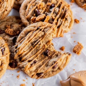 close up of a chocolate chip Biscoff cookie drizzled with melted cookie butter and cookie crumbs.