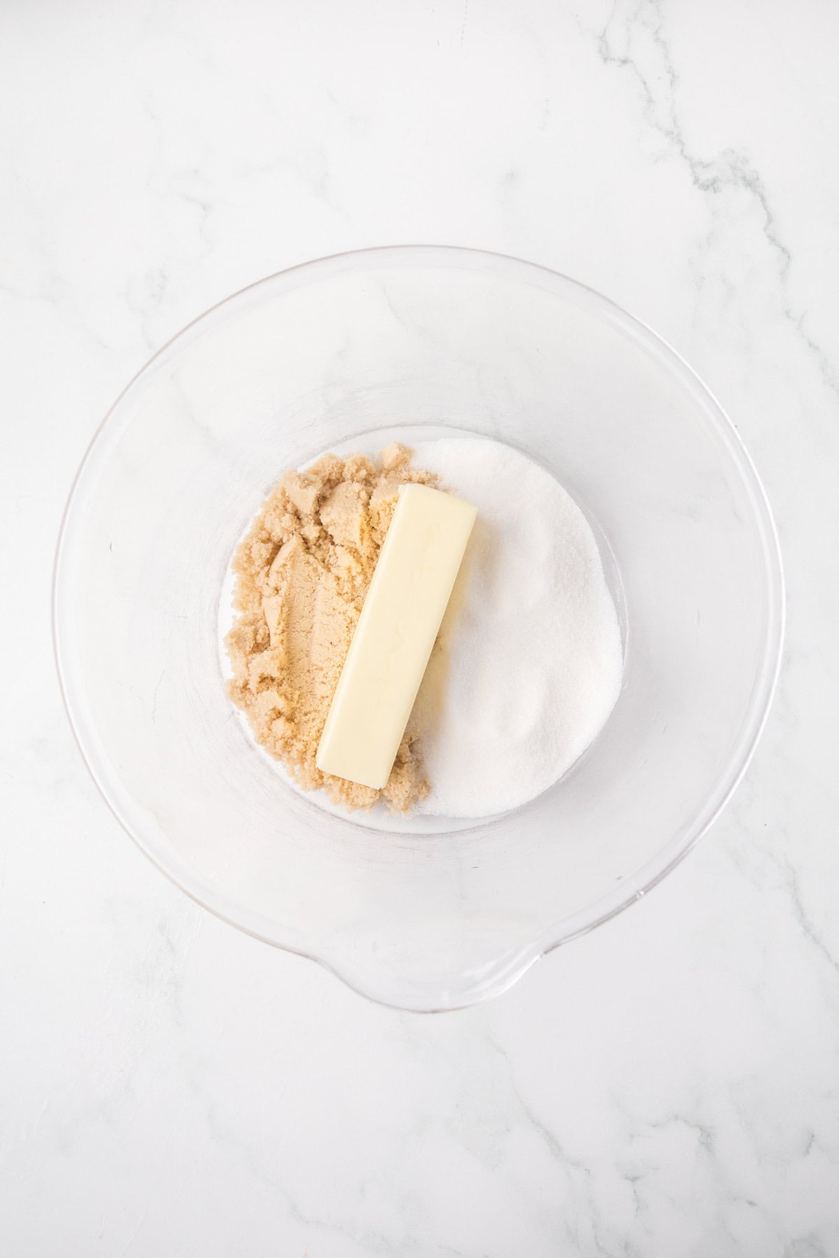 Butter, granulated sugar, and brown sugar in a mixing bowl before creaming for Oreo Milkshake Cookies.