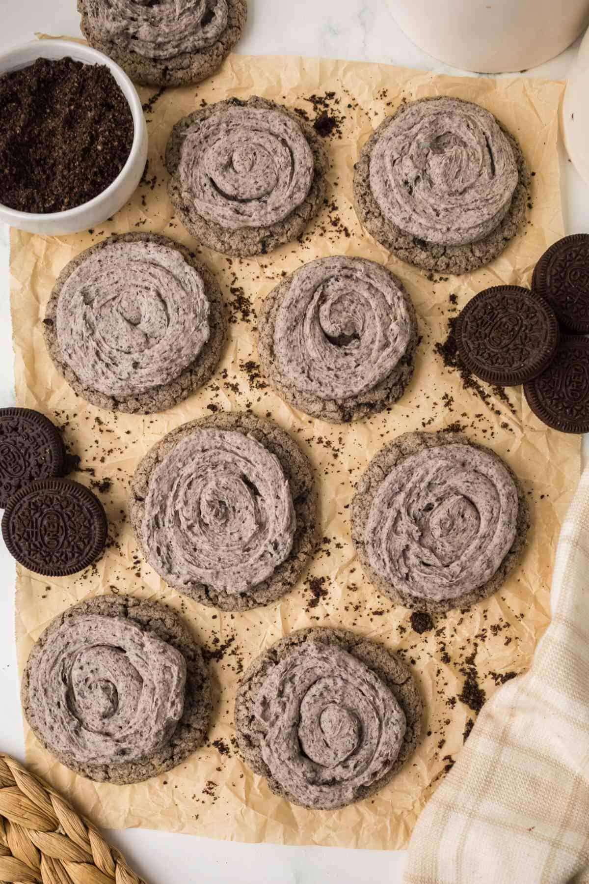 Oreo Milkshake Cookies arranged on parchment paper with crushed Oreos scattered around.