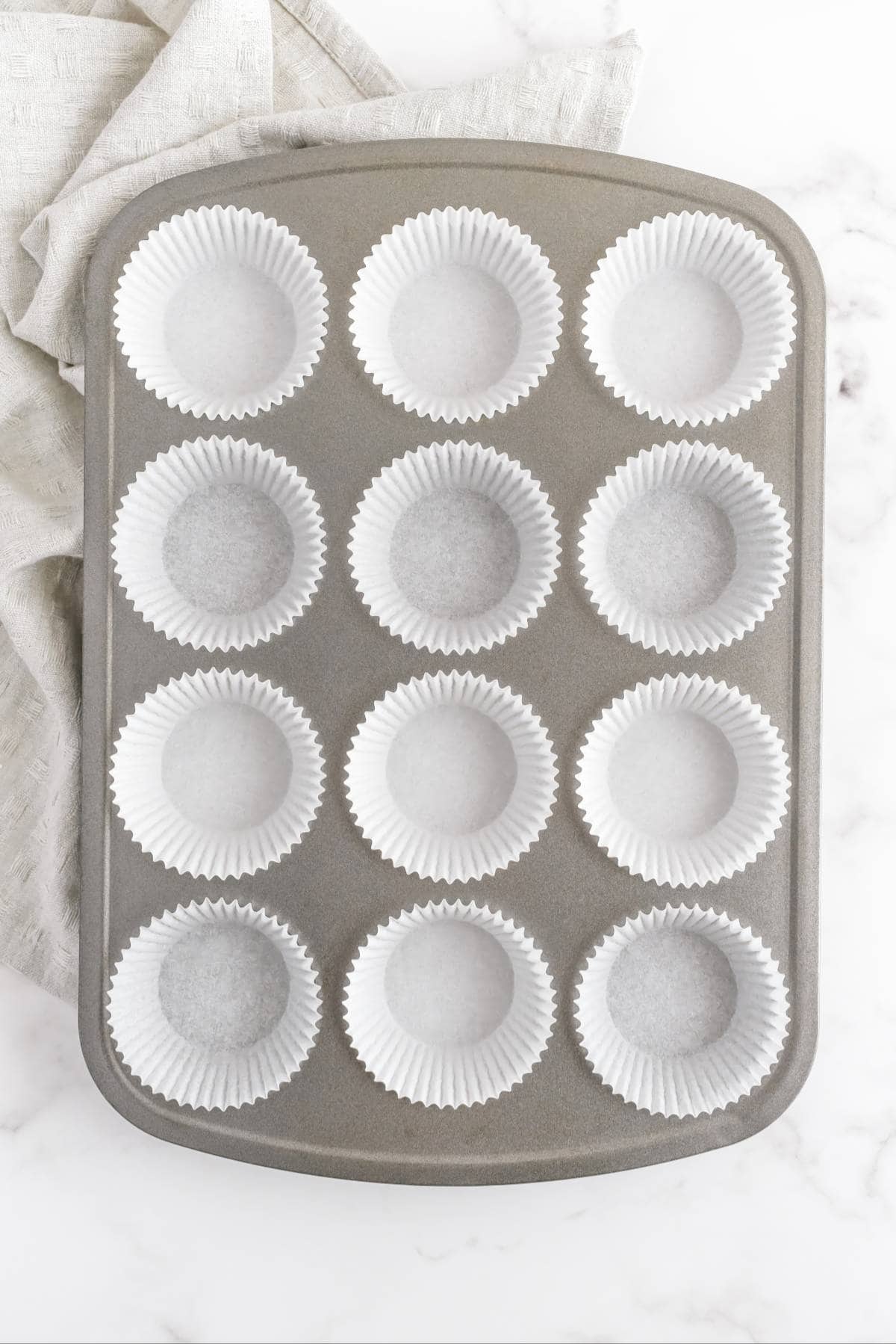 Muffin pan lined with white cupcake liners ready for baking chocolate peanut butter cupcakes