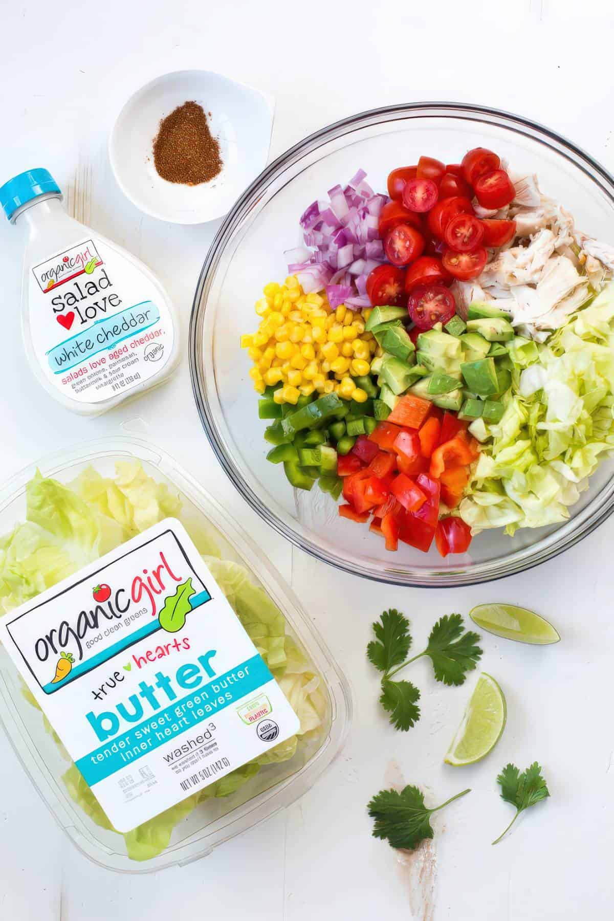 Ingredients for creamy chicken fajita chopped salad including chicken, lettuce, avocado, corn, tomatoes and peppers in a bowl