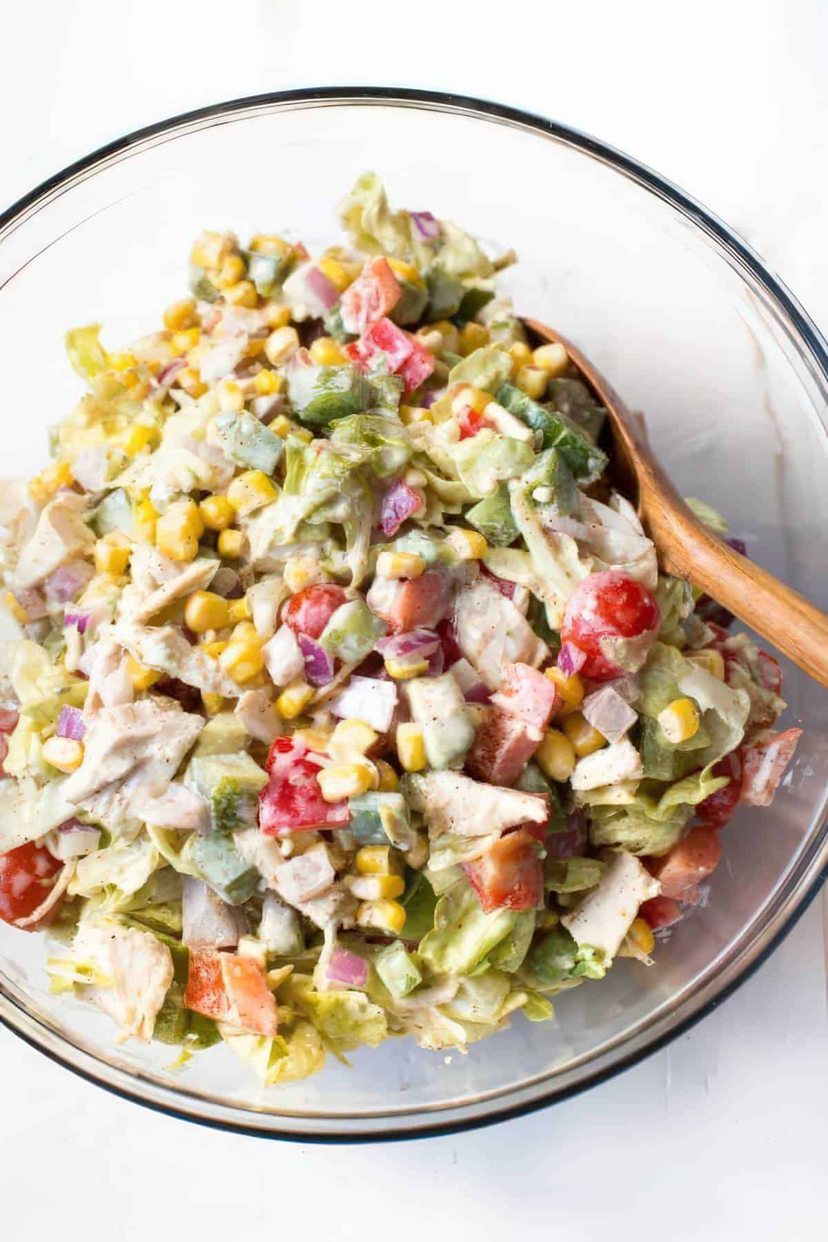 Creamy chicken fajita chopped salad with corn, avocado, tomatoes, peppers and creamy dressing in a bowl