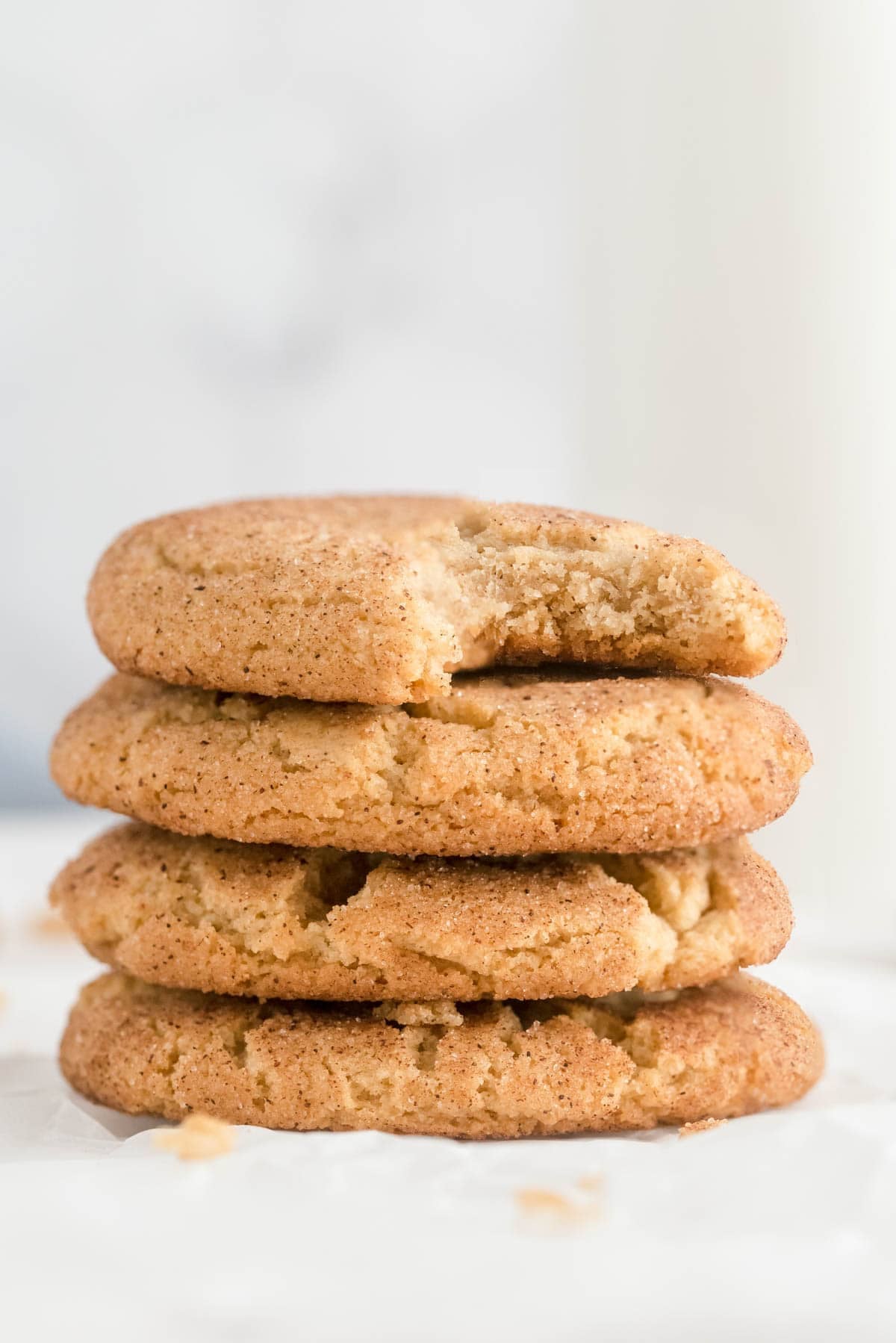 Stack of soft snickerdoodle cookies with a bite showing tender center and cinnamon sugar coating