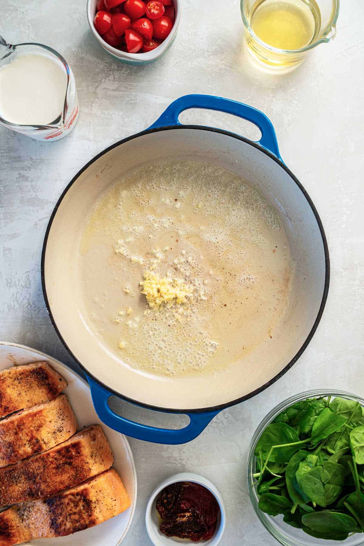 Garlic cooking in melted butter in a skillet as the base for creamy Tuscan salmon sauce.