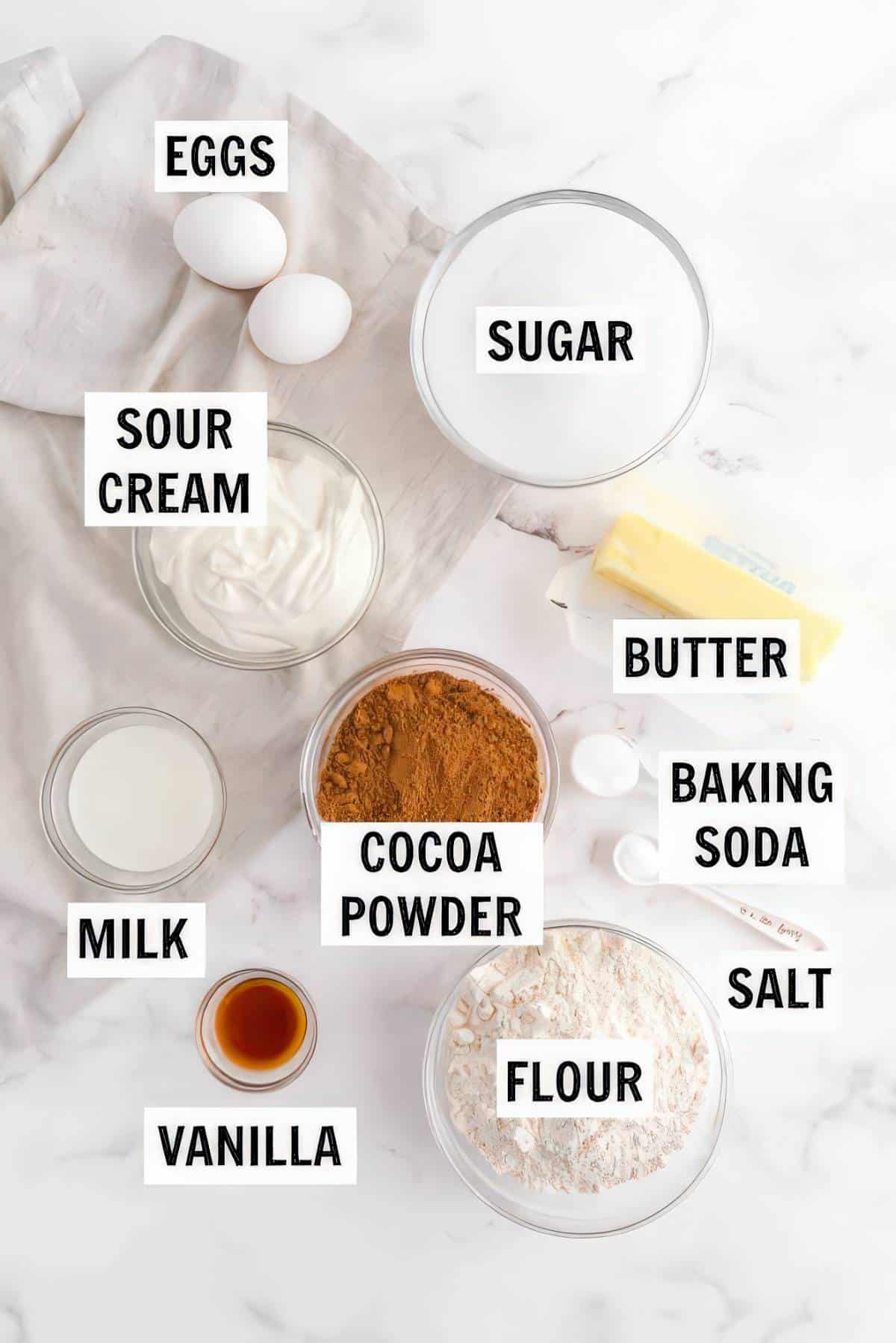 Ingredients for chocolate peanut butter cupcakes including cocoa powder, flour, sugar, eggs, sour cream and milk