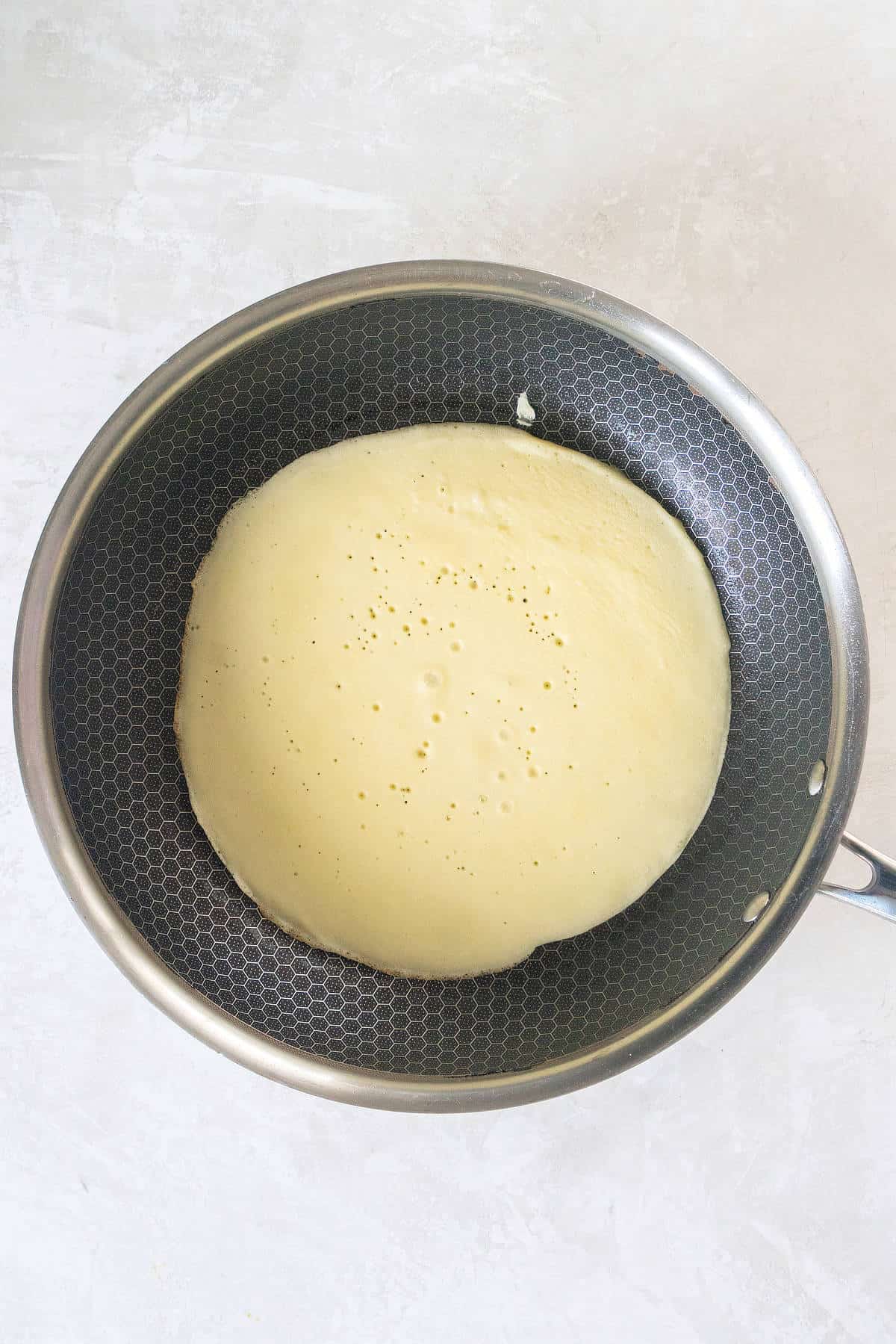 Thin pancake batter poured into skillet and spread evenly for pancake roll ups