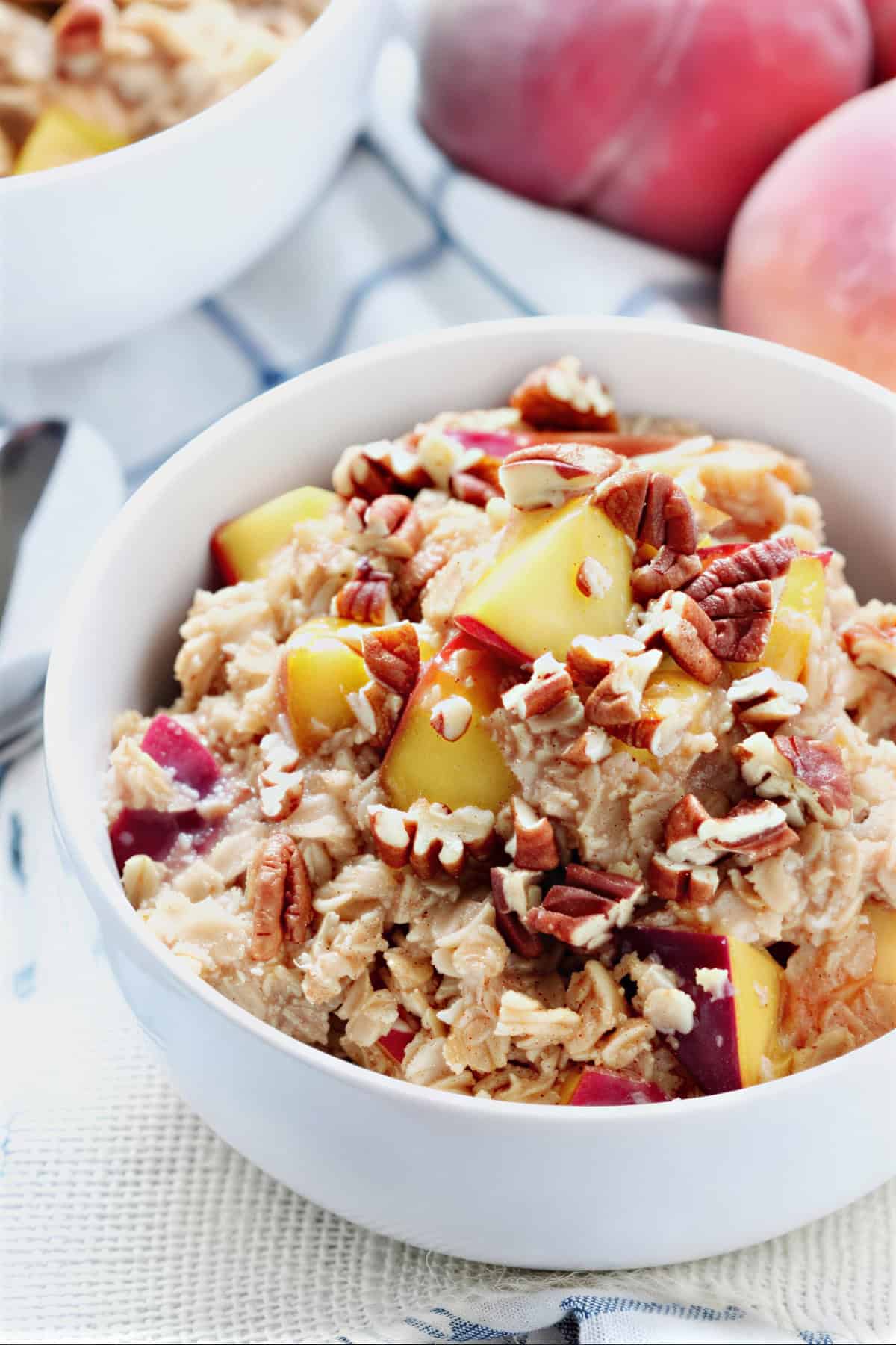 Close-up overhead shot of peach cobbler oatmeal with diced peaches and crunchy pecans.