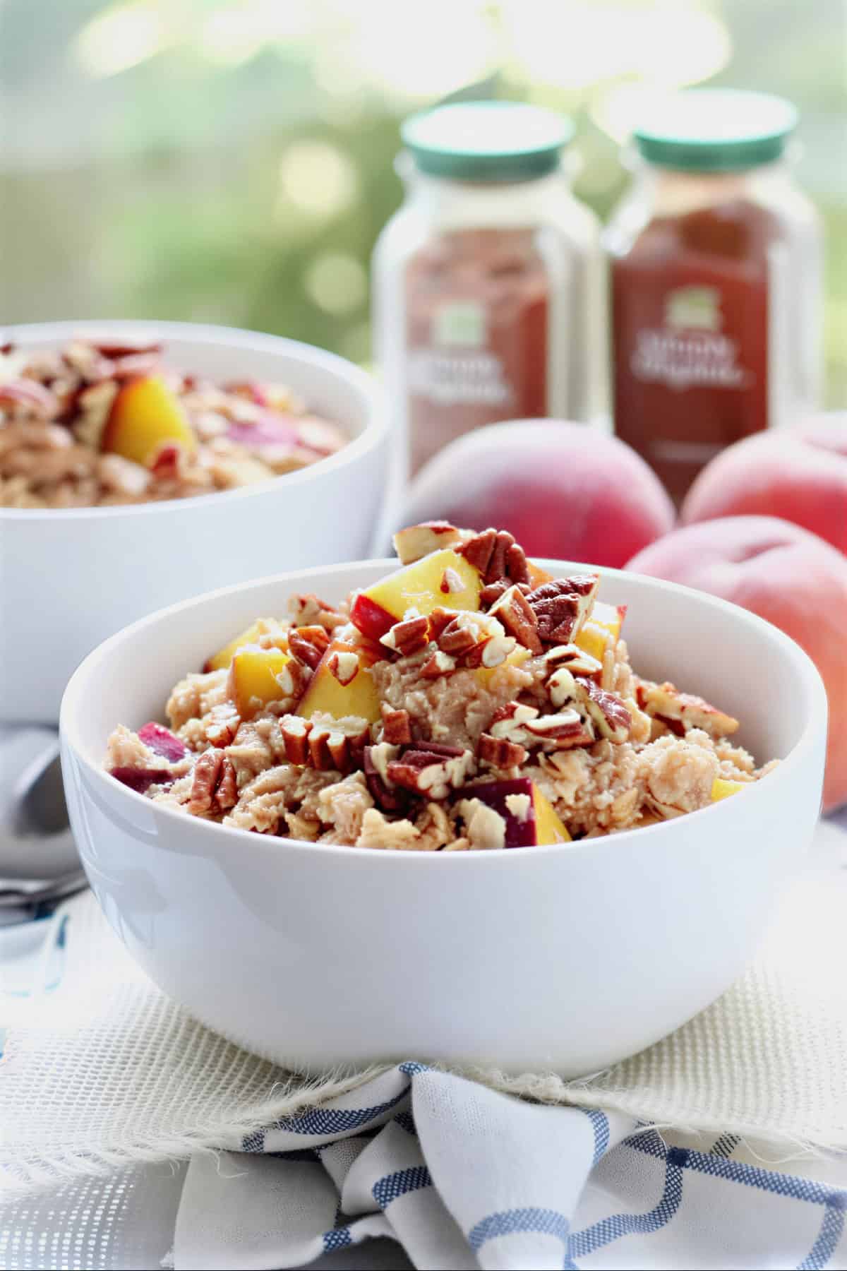 Peach cobbler oatmeal with diced peaches and pecans served in a white bowl.