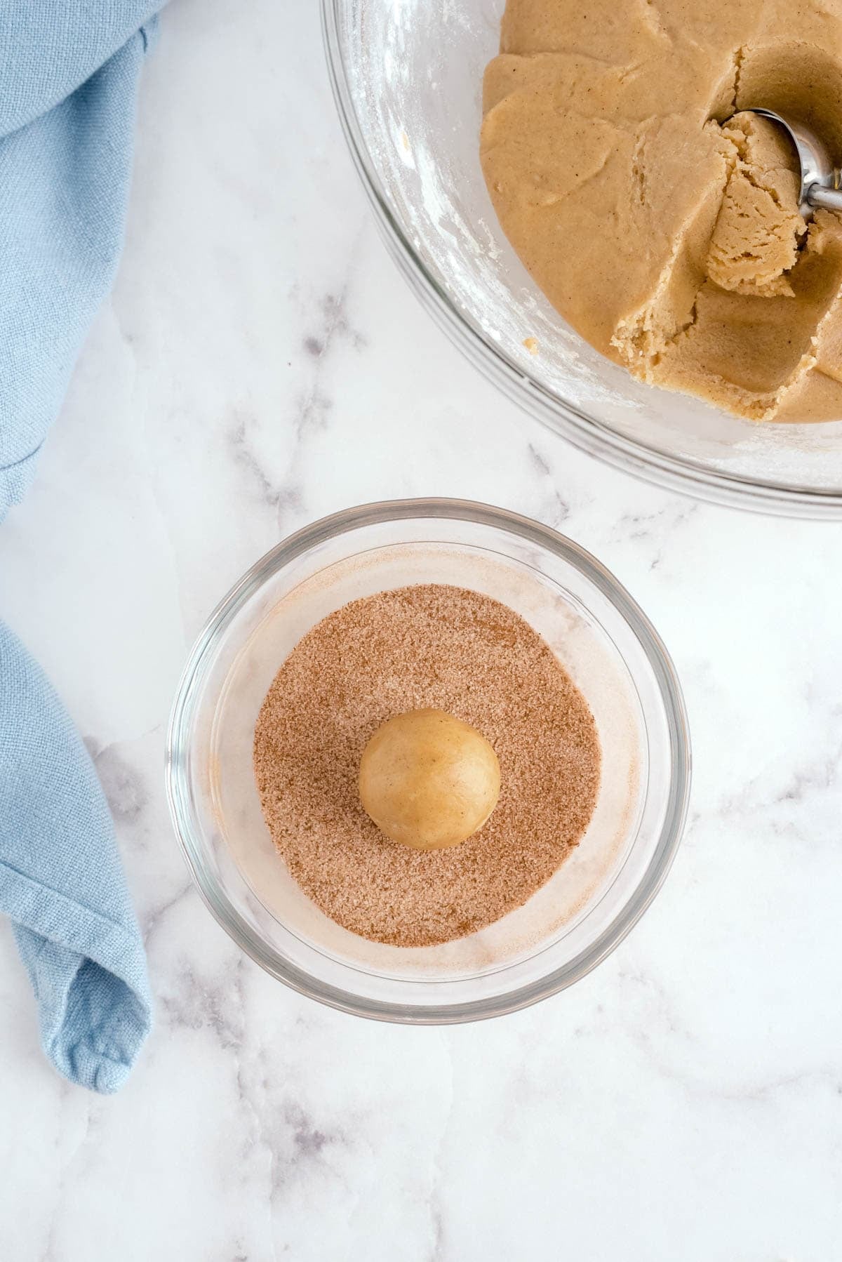 Snickerdoodle cookie dough ball rolled in cinnamon sugar coating before baking