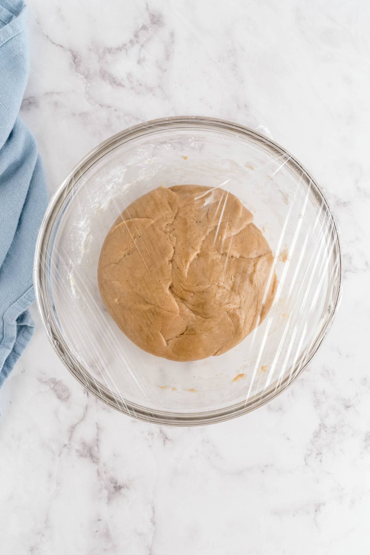 Snickerdoodle cookie dough ready to chill in a bowl covered with plastic wrap before baking