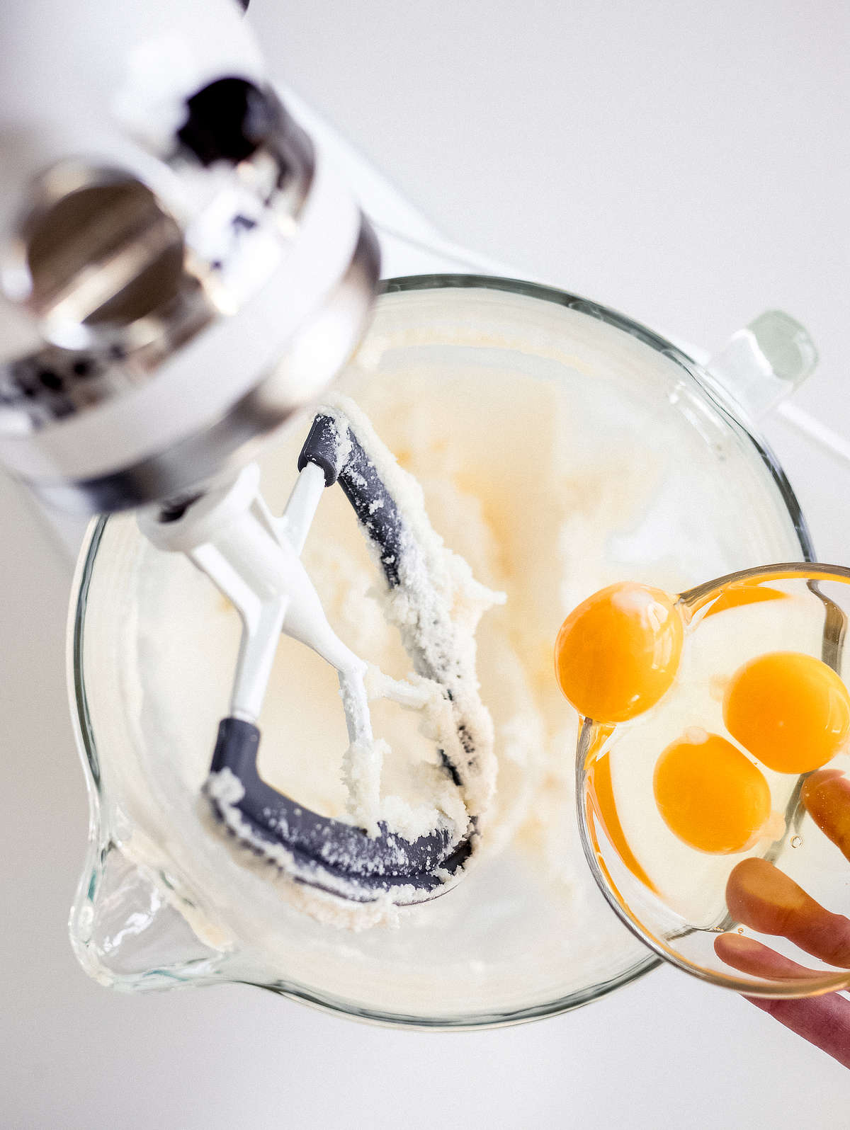 adding eggs to creamed butter and sugar mixture in stand mixer for lemon pound cake