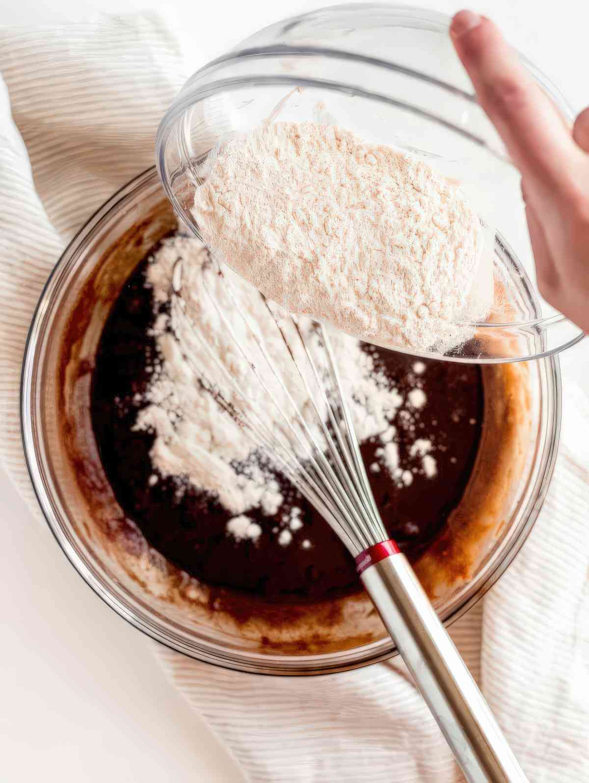 Pouring flour into chocolate mixture to make brownie batter