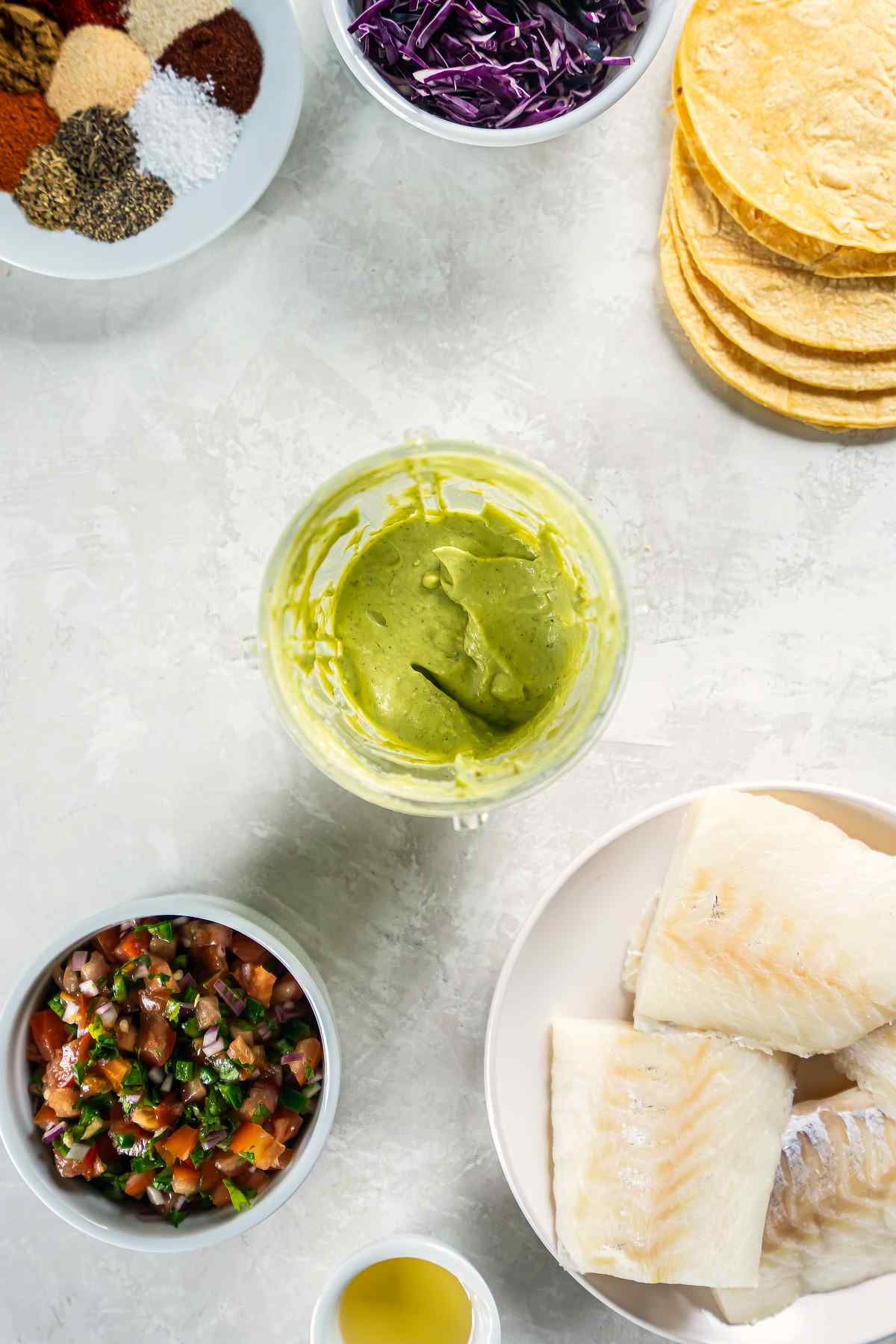 Blended avocado cilantro sauce in a food processor for cod tacos