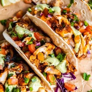 Close-up of blackened cod tacos with avocado cilantro sauce, fresh pico de gallo, and shredded cabbage