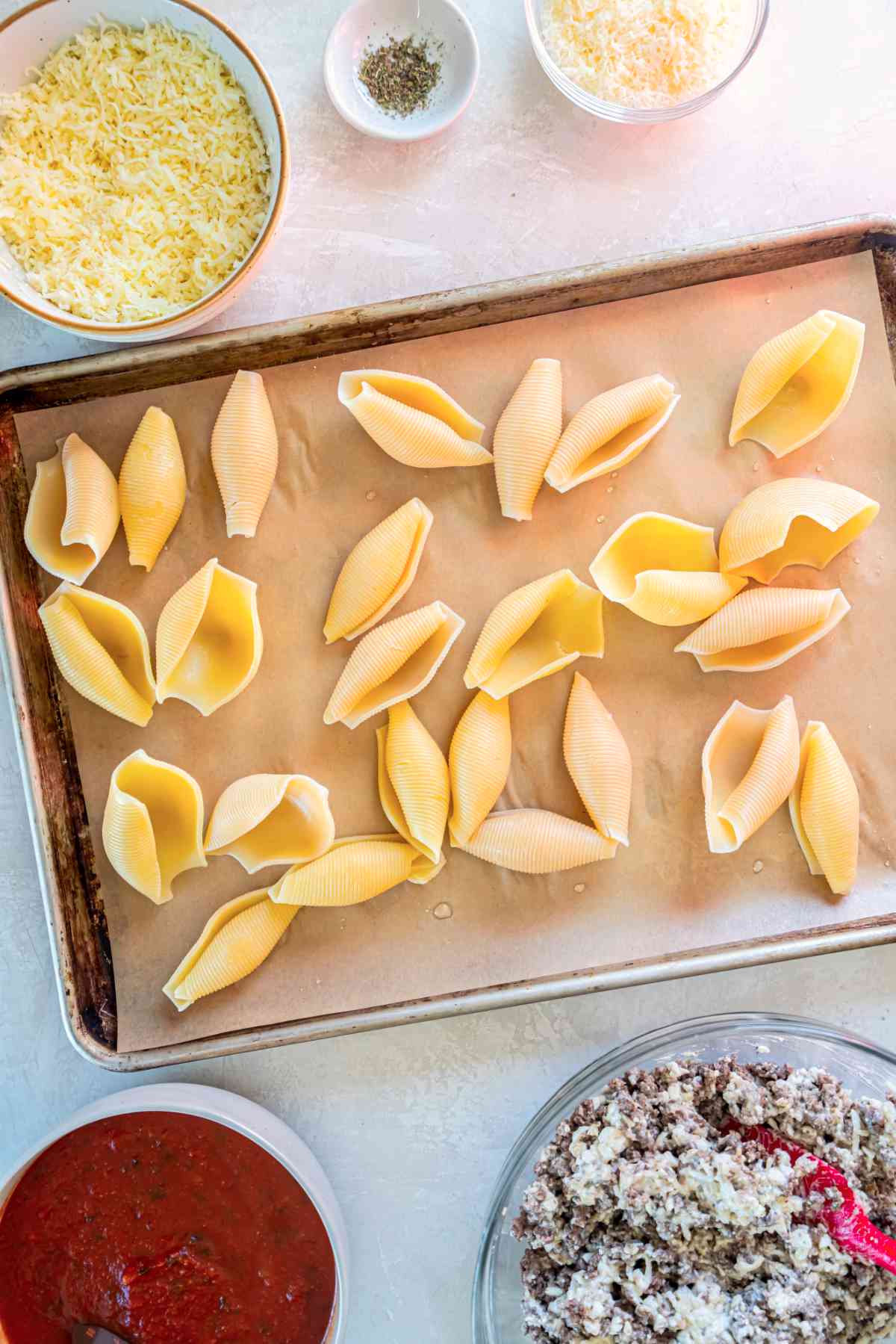 Cooked jumbo pasta shells spread on a baking sheet to cool before stuffing