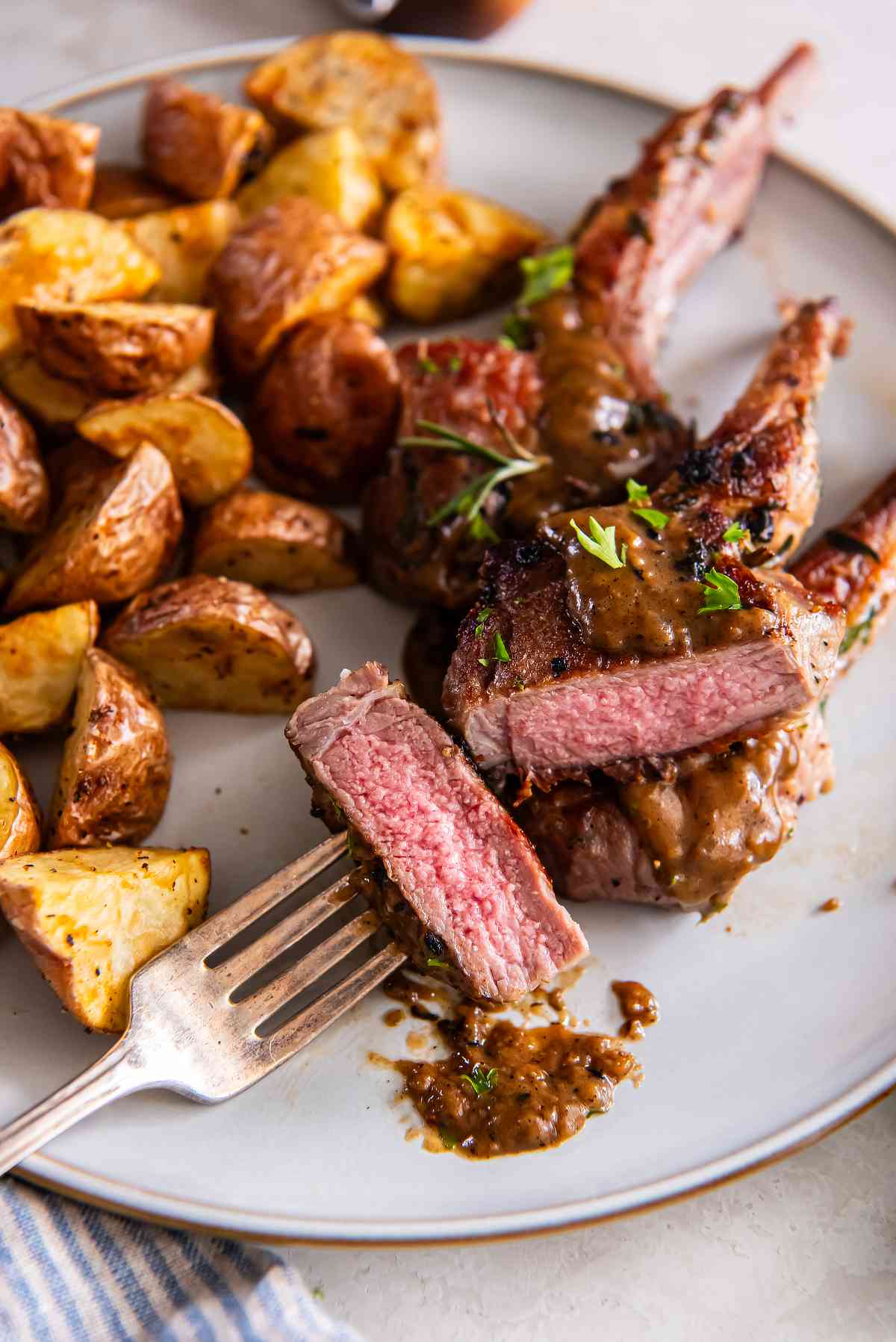 Garlic herb lamb cutlets cooked medium rare with pan sauce and roasted potatoes