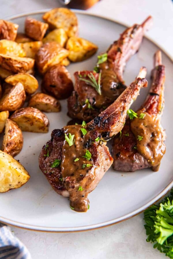 Garlic herb lamb cutlets served with roasted potatoes and pan sauce on a plate