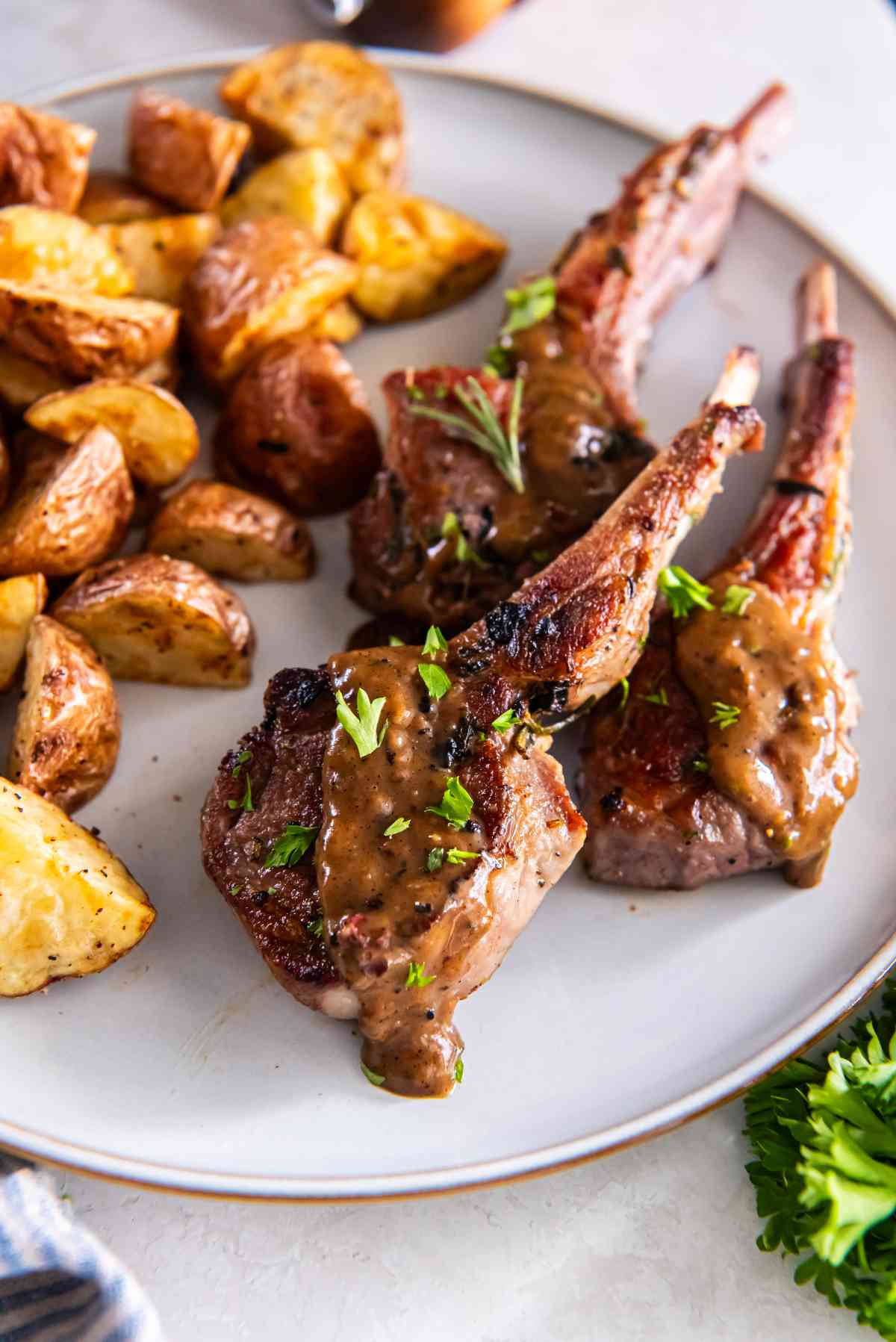 Garlic herb lamb cutlets served with roasted potatoes and pan sauce on a plate