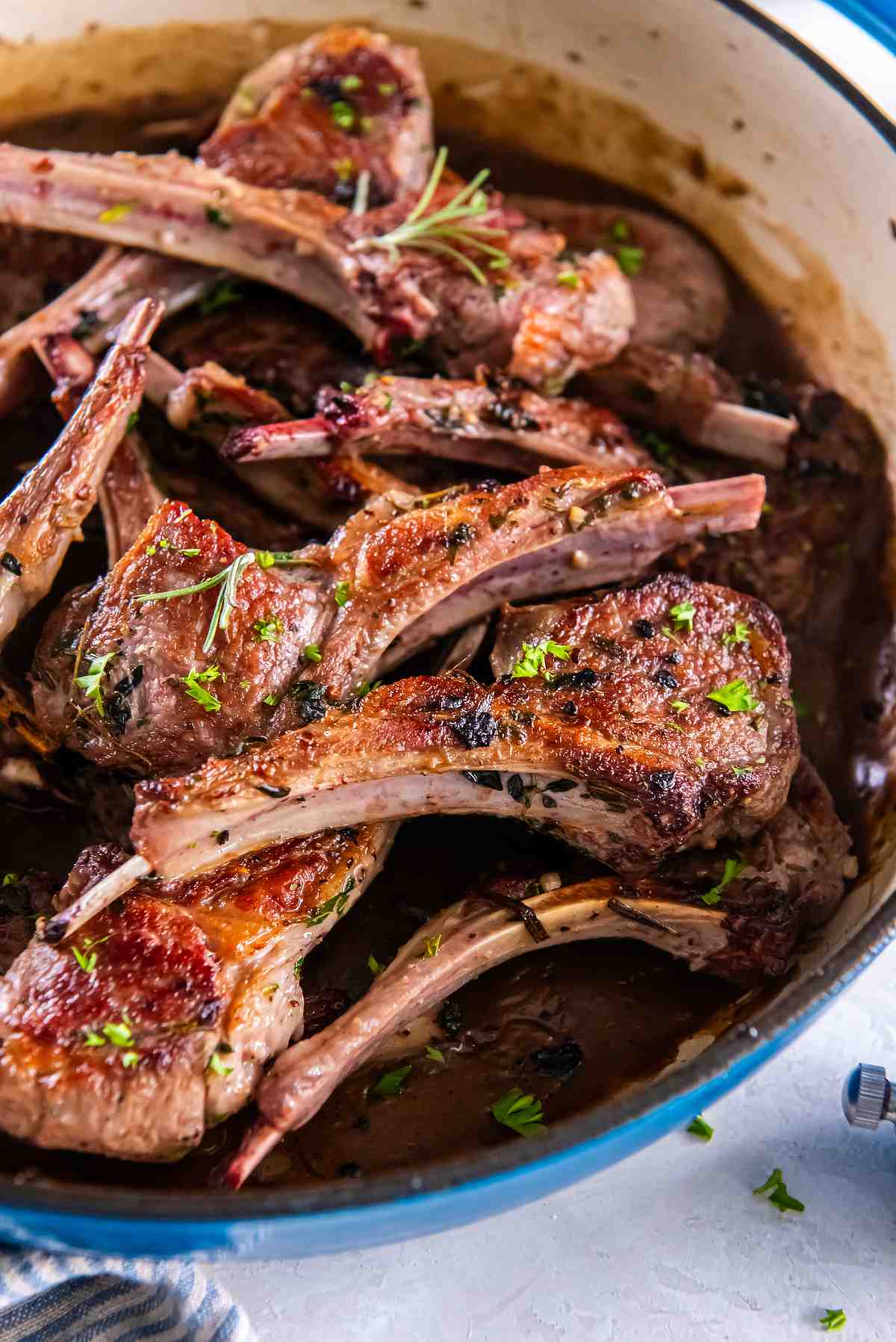 Lamb cutlets cooking in a skillet with garlic herb pan sauce