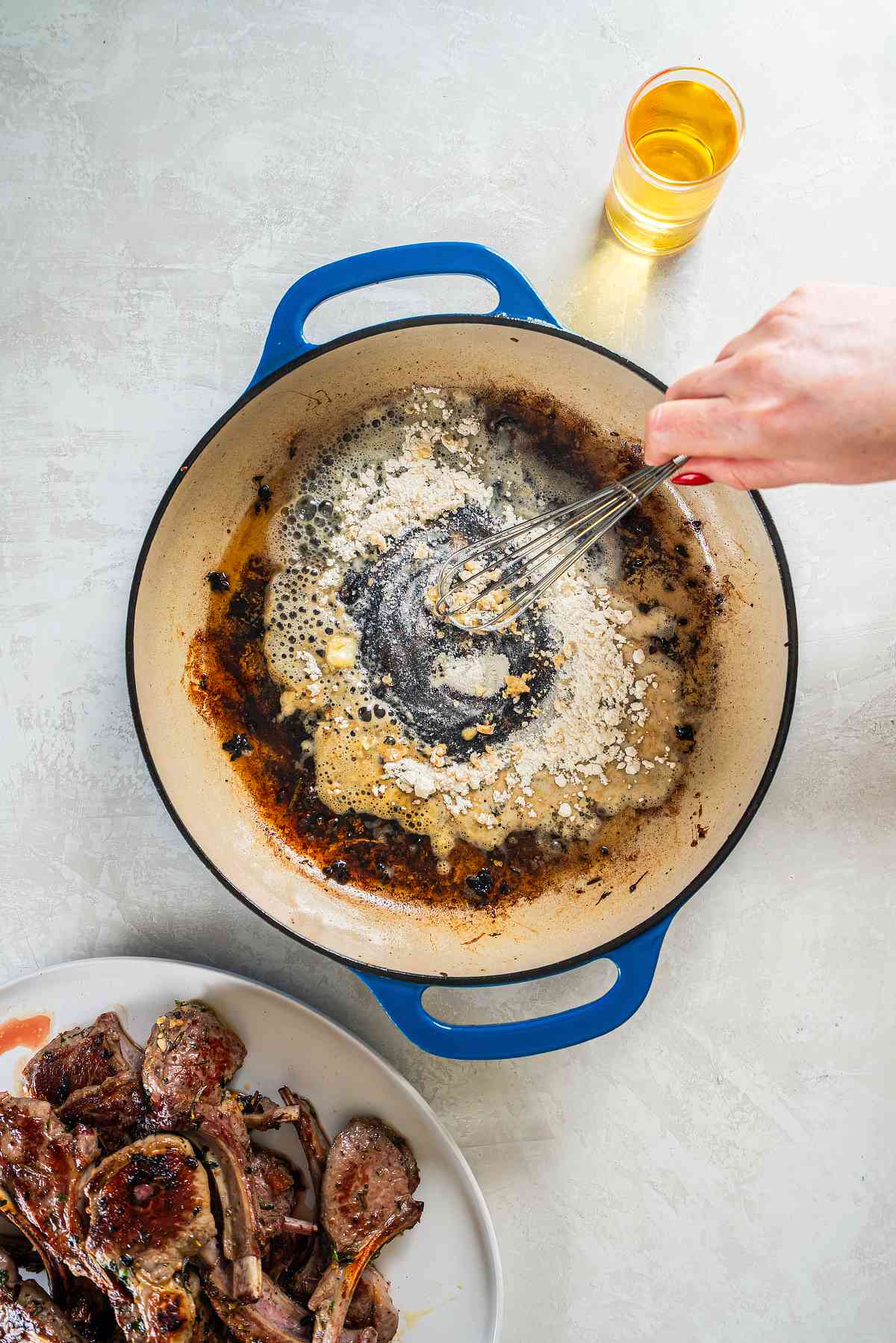 Whisking butter and flour in a skillet to create a base for lamb pan sauce