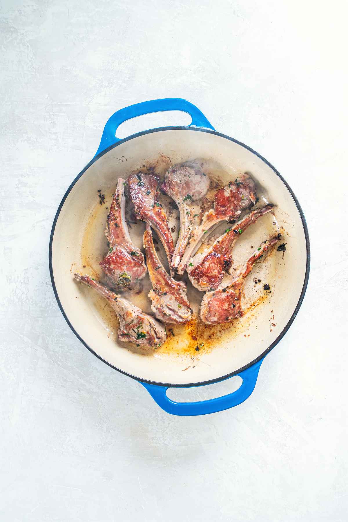 Lamb cutlets searing in a hot skillet to create a golden crust