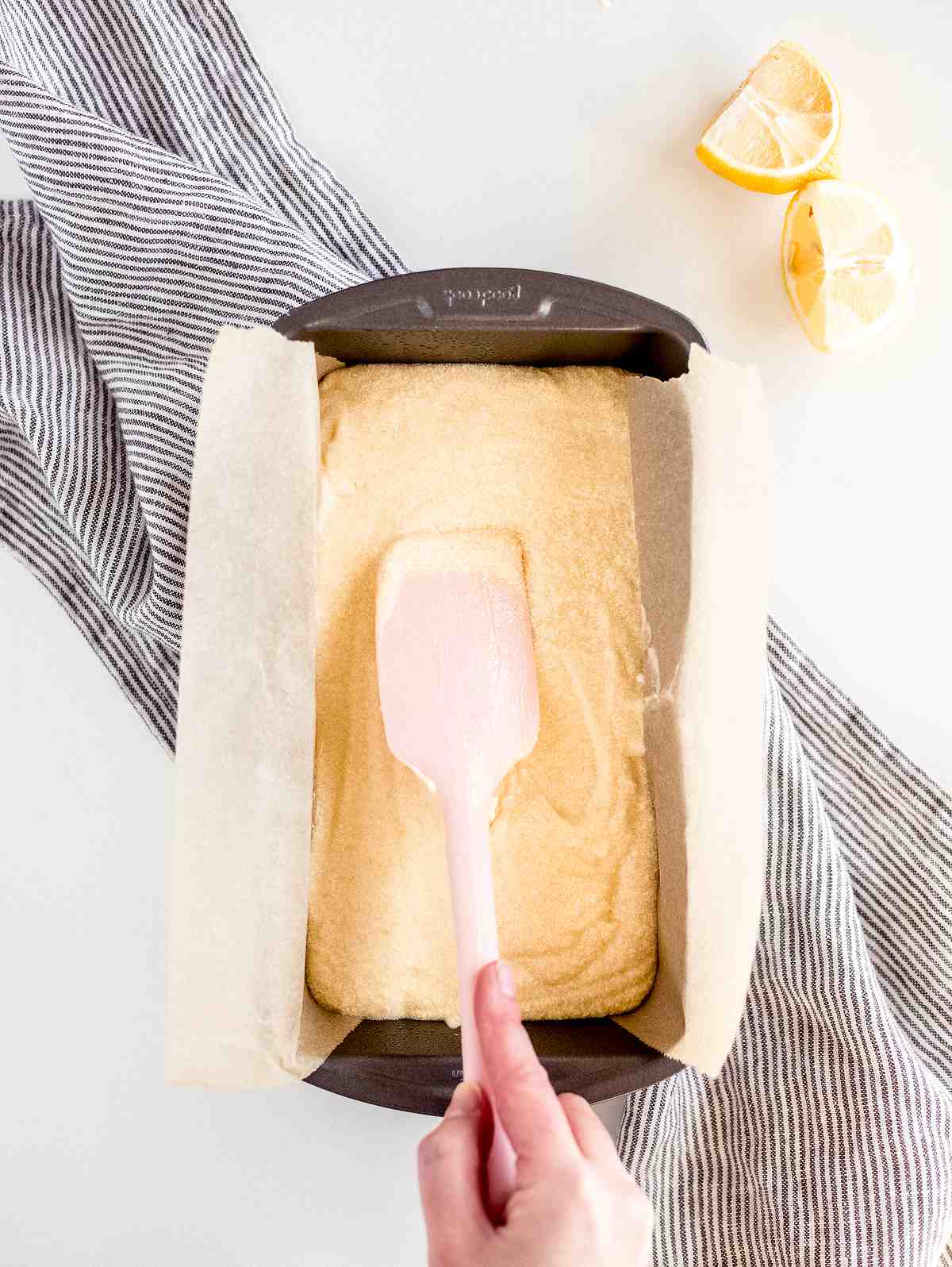 smoothing lemon pound cake batter in a parchment lined loaf pan before baking