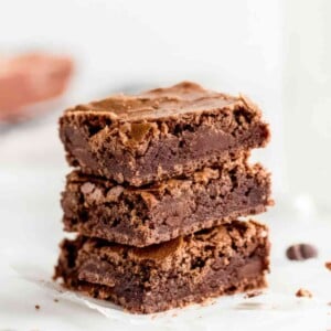 Alt: Stack of chewy brownies showing dense fudgy center and crackly tops