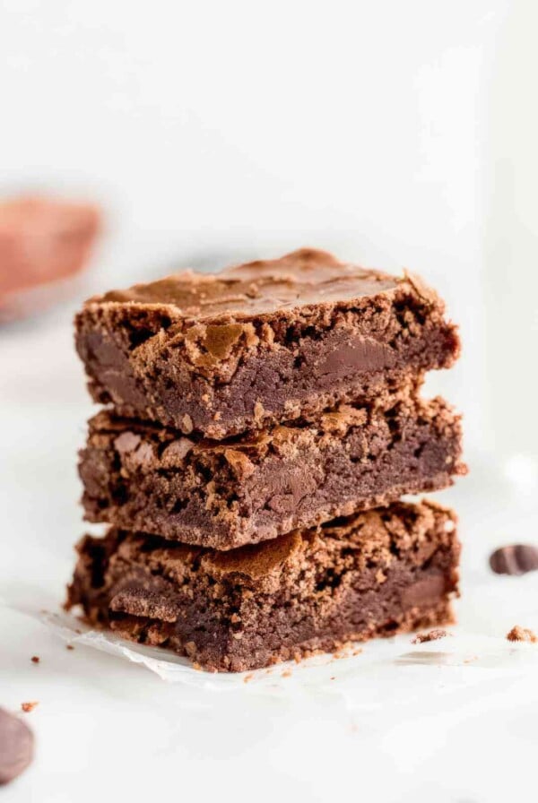 Alt: Stack of chewy brownies showing dense fudgy center and crackly tops