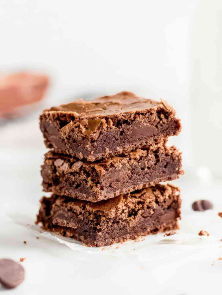 Alt: Stack of chewy brownies showing dense fudgy center and crackly tops