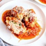 Stuffed shells with ground beef and cottage cheese served on a plate with marinara sauce and Parmesan