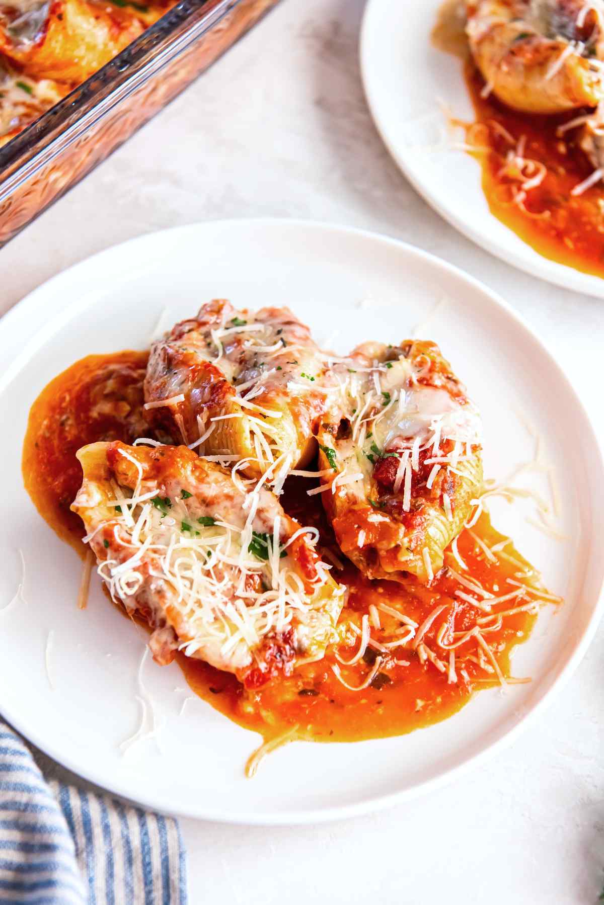 Stuffed shells with ground beef and cottage cheese served on a plate with marinara sauce and Parmesan
