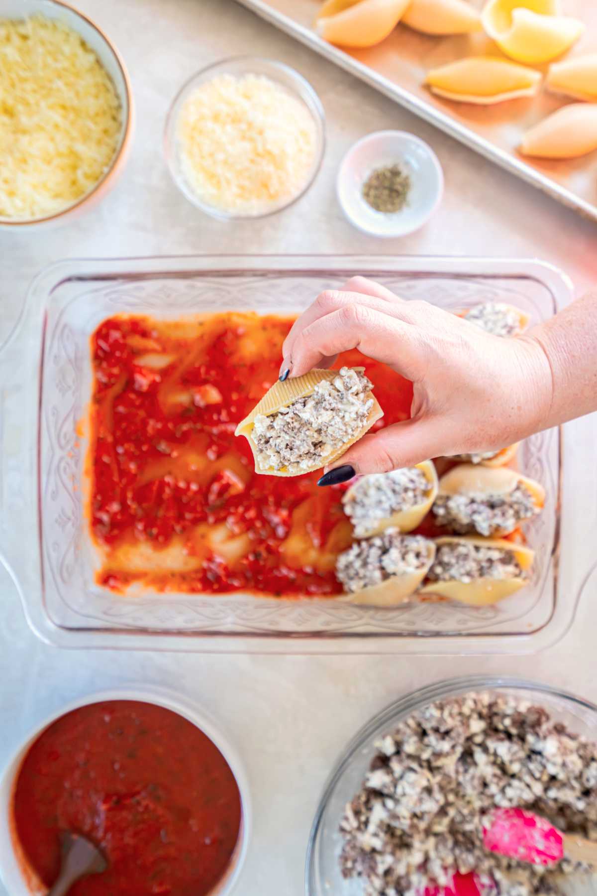 Hand filling jumbo pasta shells with ground beef and cottage cheese mixture
