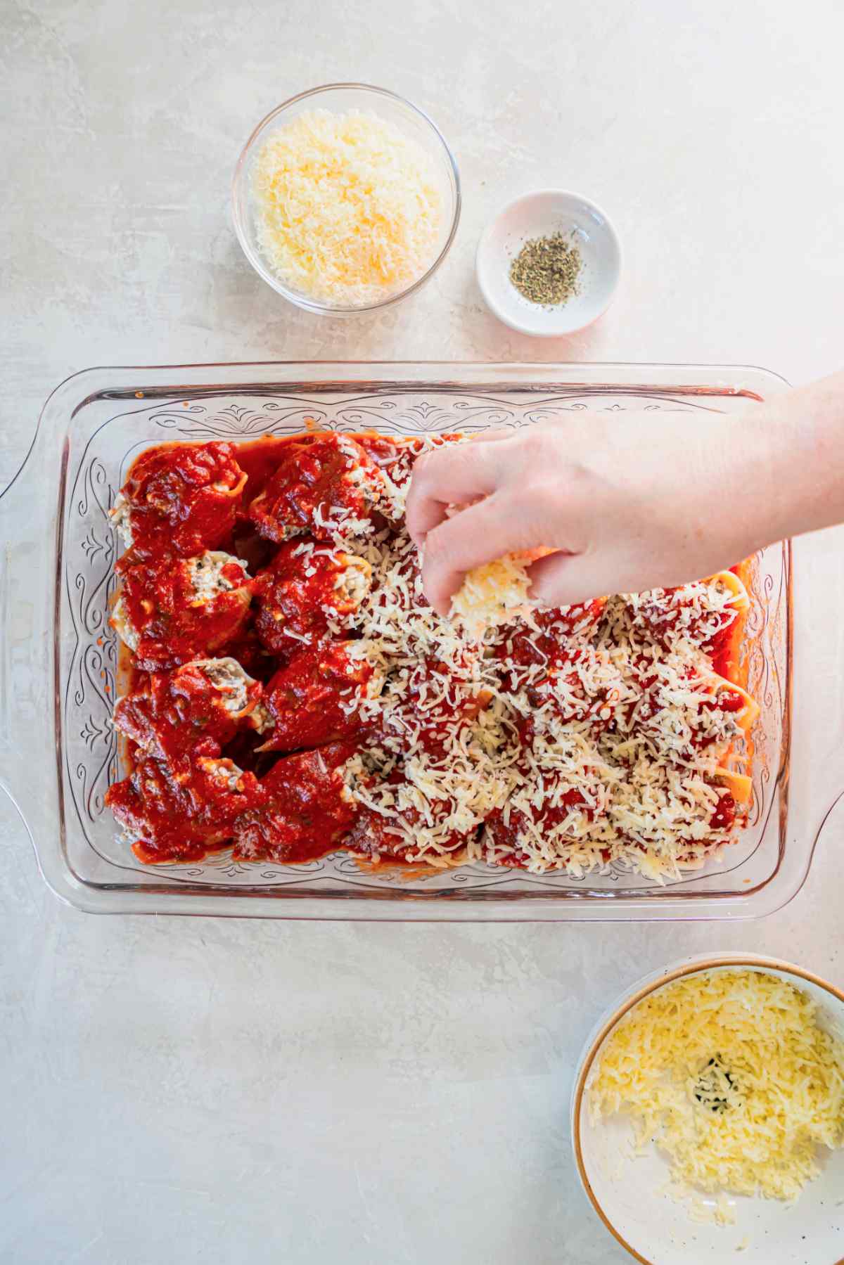 Stuffed shells topped with shredded mozzarella and marinara sauce before baking