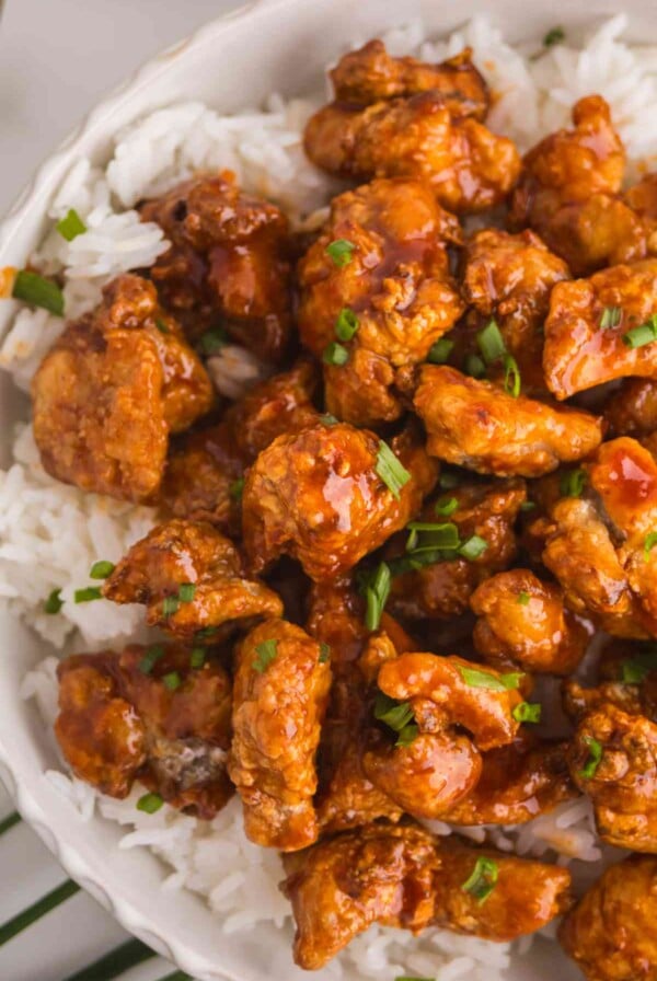 Crispy Gochujang Chicken served over white rice with sticky Korean-style sauce and green onions.