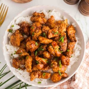 Bowl of Crispy Gochujang Chicken served over rice with green onions for an easy takeout-inspired dinner.