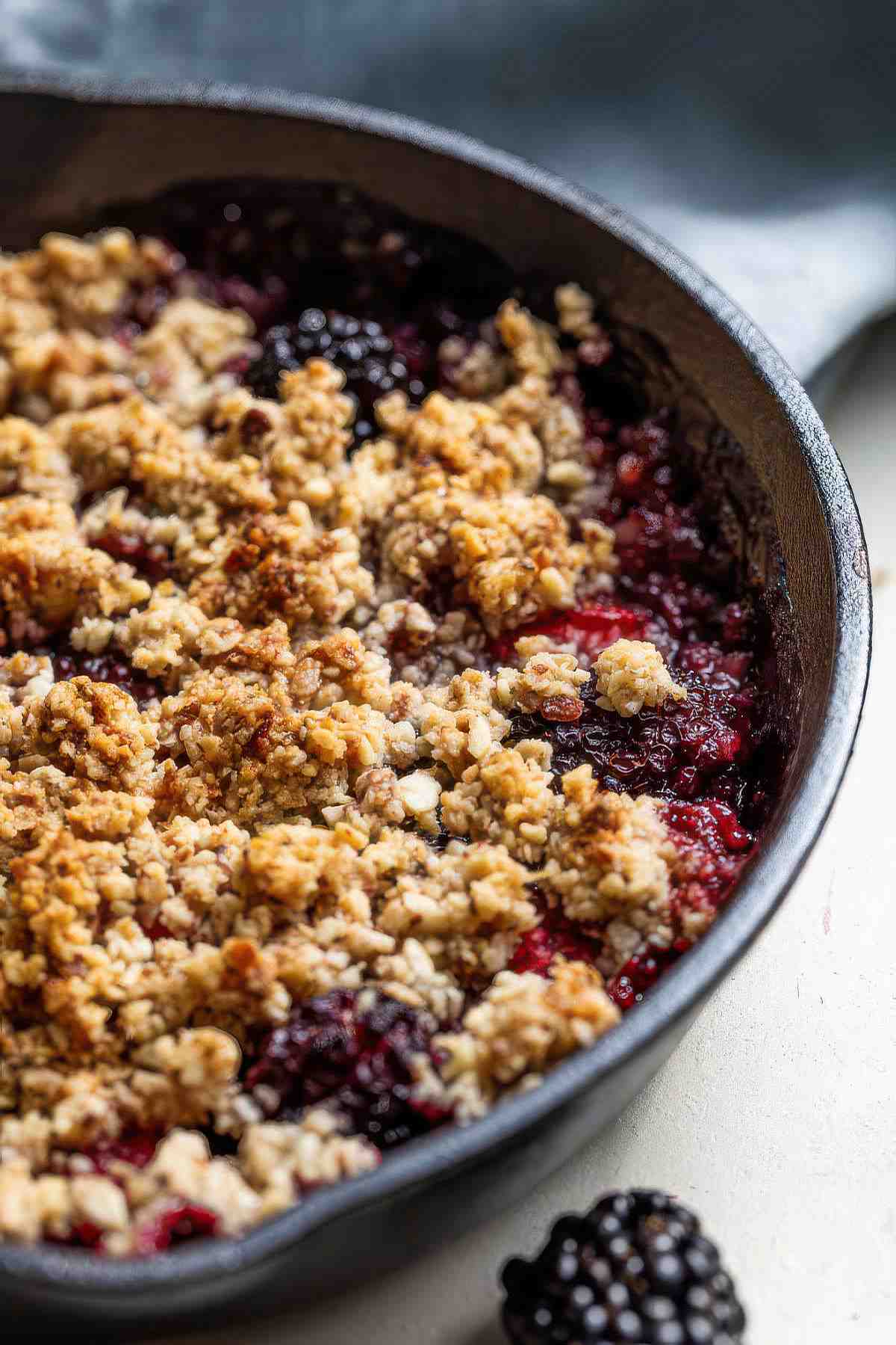 Close-up of berry almond crisp with golden almond oat topping and bubbling berries.