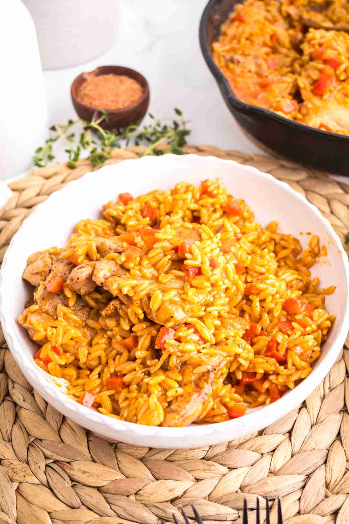 Bowl of creamy Cajun chicken orzo made with chicken thighs, orzo pasta, Cajun seasoning, and red bell peppers.