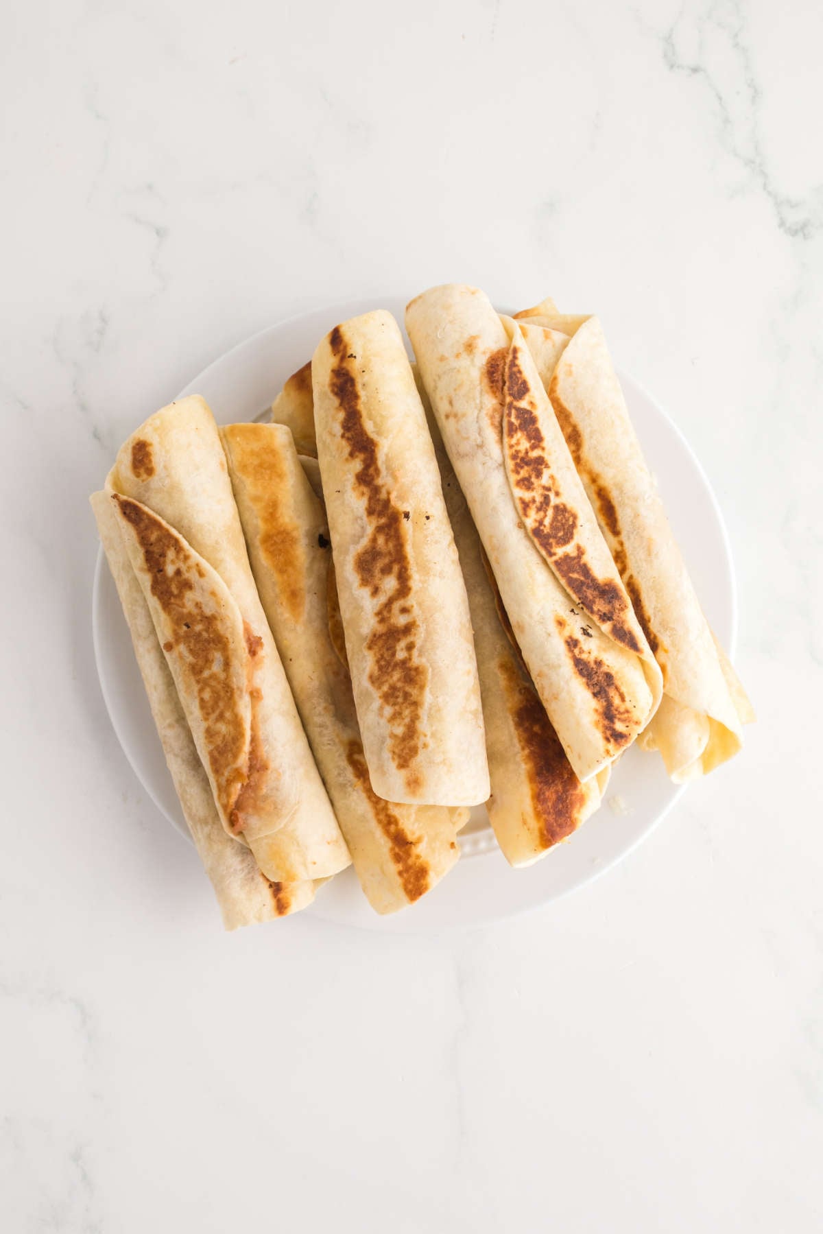 Crispy bean and cheese taquitos on a plate, golden brown and ready to serve