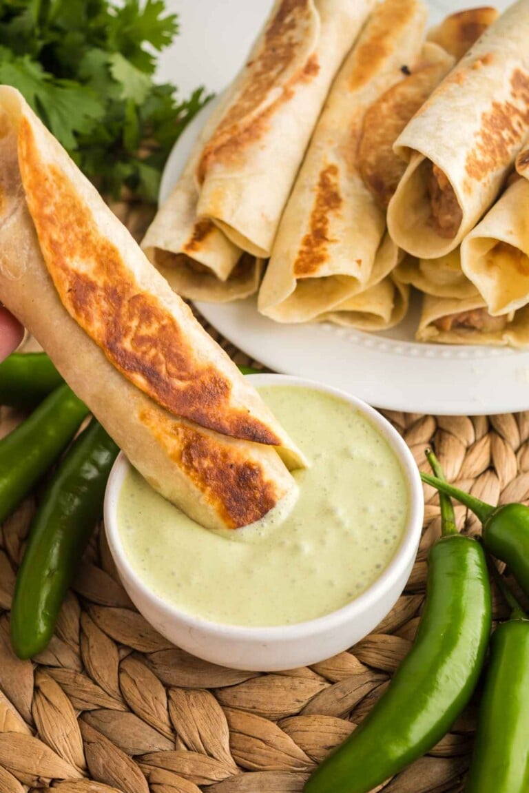 Crispy bean and cheese taquito dipped into creamy jalapeño ranch sauce