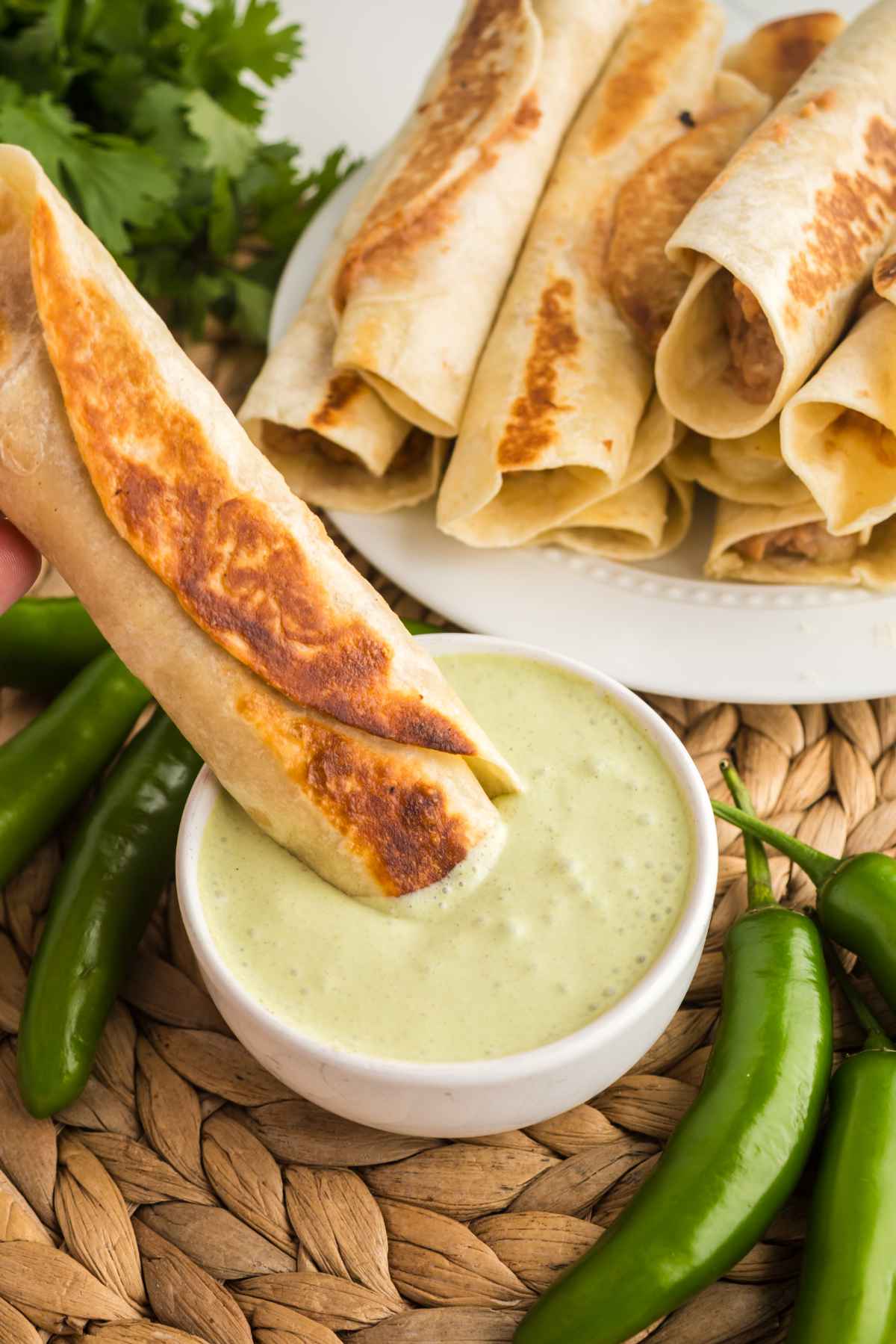 Crispy bean and cheese taquito dipped into creamy jalapeño ranch sauce
